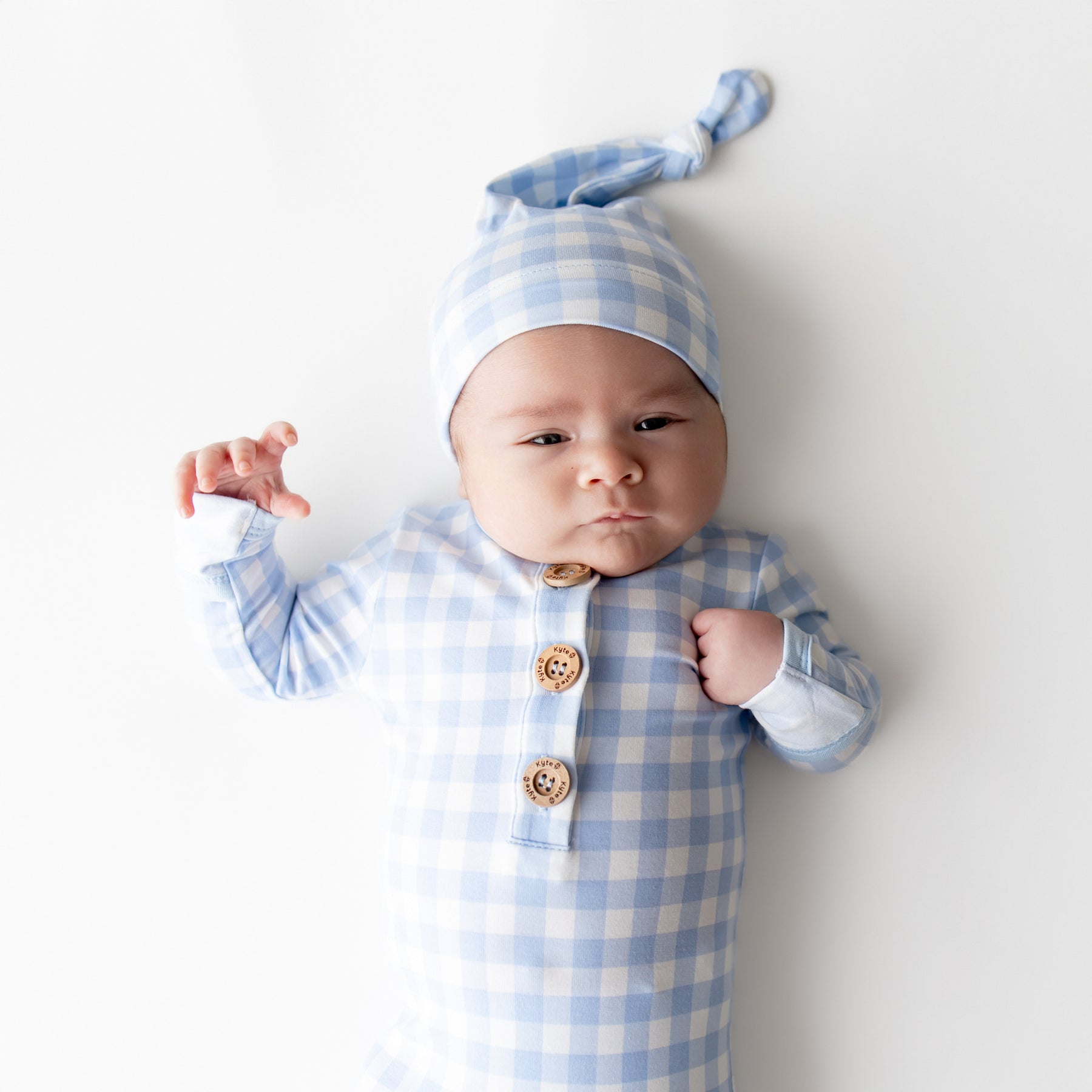 Close up of newborn wearing the Knotted Gown with Hat Set in Gingham Breeze