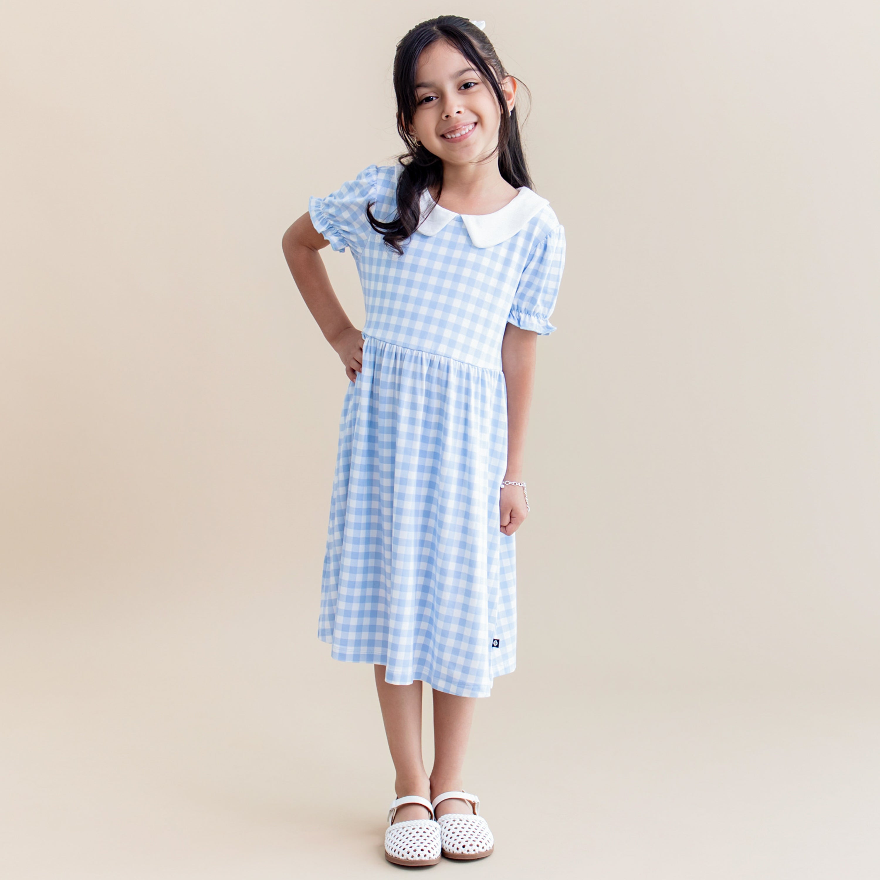 Young girl posing wearing the Peter Pan Collar Dress in Gingham Breeze