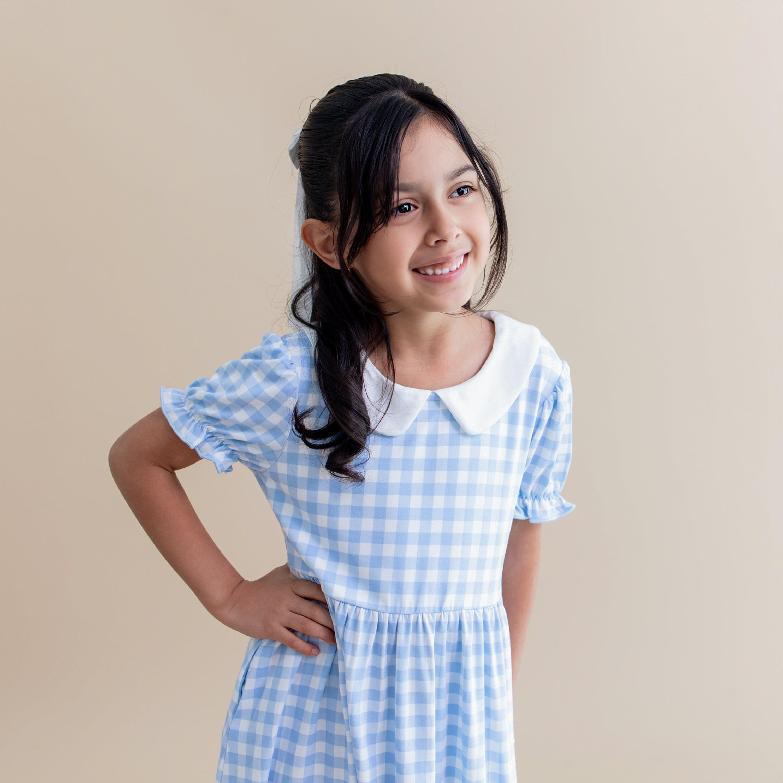 Close up of the puff sleeves and white neck trim on the Peter Pan Collar Dress in Gingham Breeze shown on a girl model