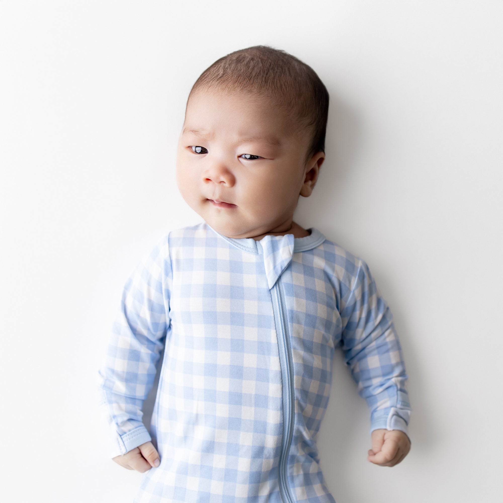Close up of infant wearing the Zippered Footie in Gingham Breeze
