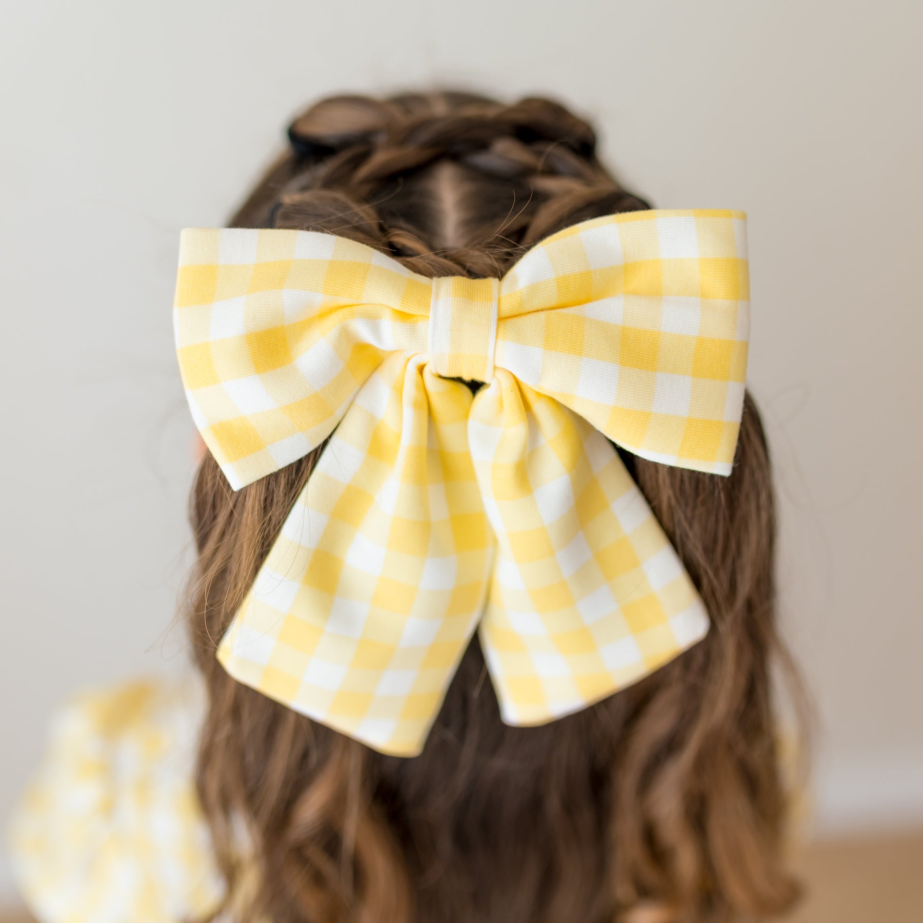 Close up of the Large Alligator Clip Bow in Gingham Chamomile shown in a young girls hair