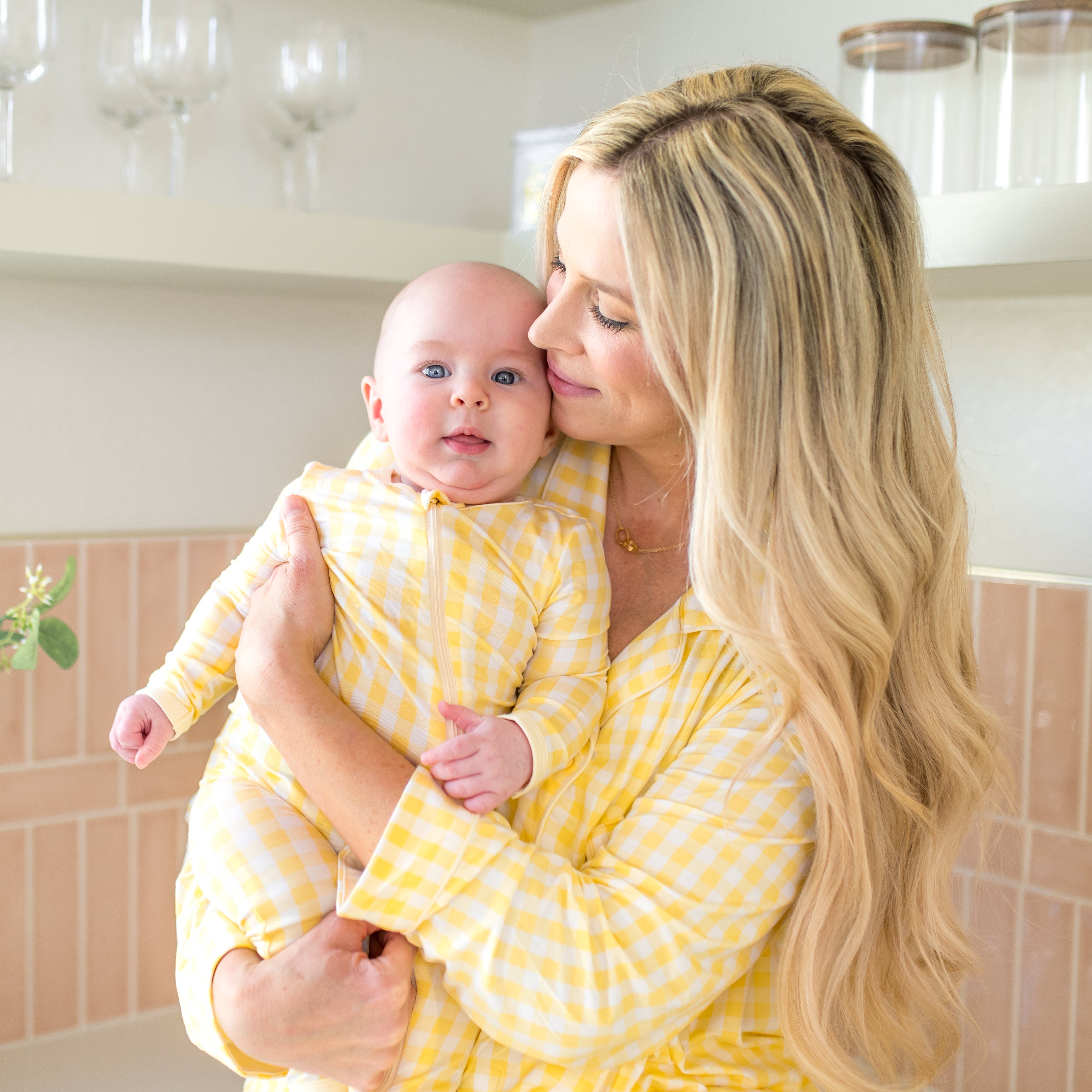 Mother wearing women's long sleeve pajama set in Gingham Chamomile matching her infant wearing the Zippered Romper in Gingham Chamomile