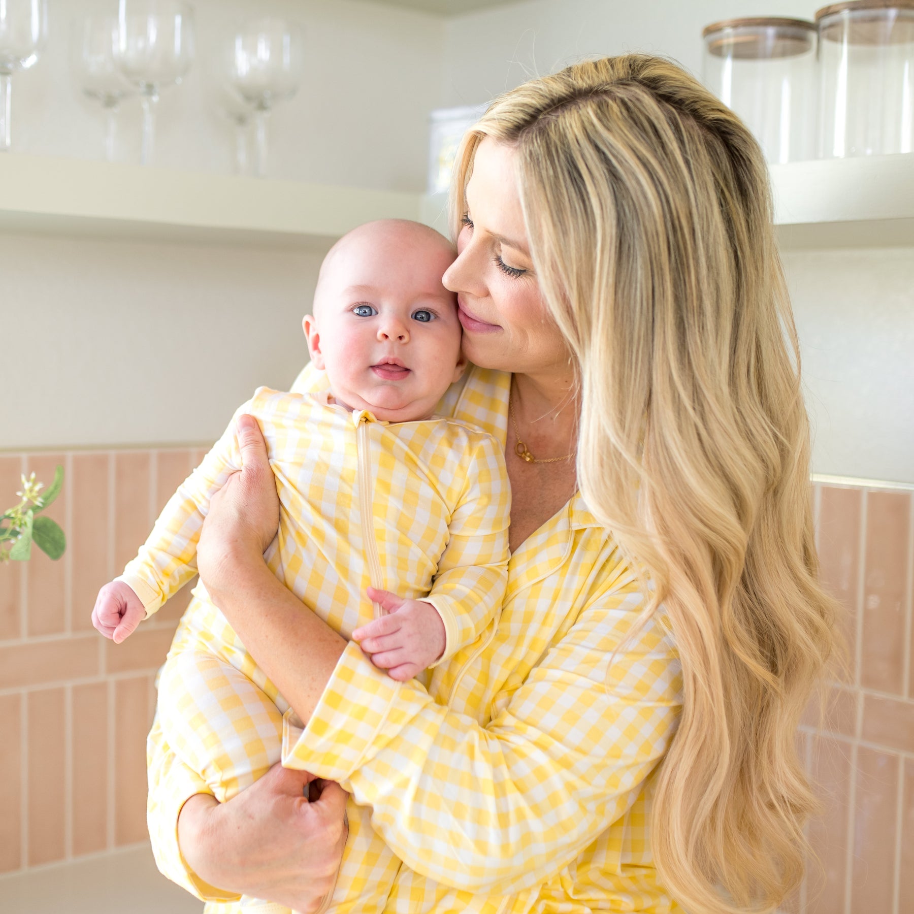 Mother wearing women's long sleeve pajama set in Gingham Chamomile matching her infant wearing the Zippered Romper in Gingham Chamomile