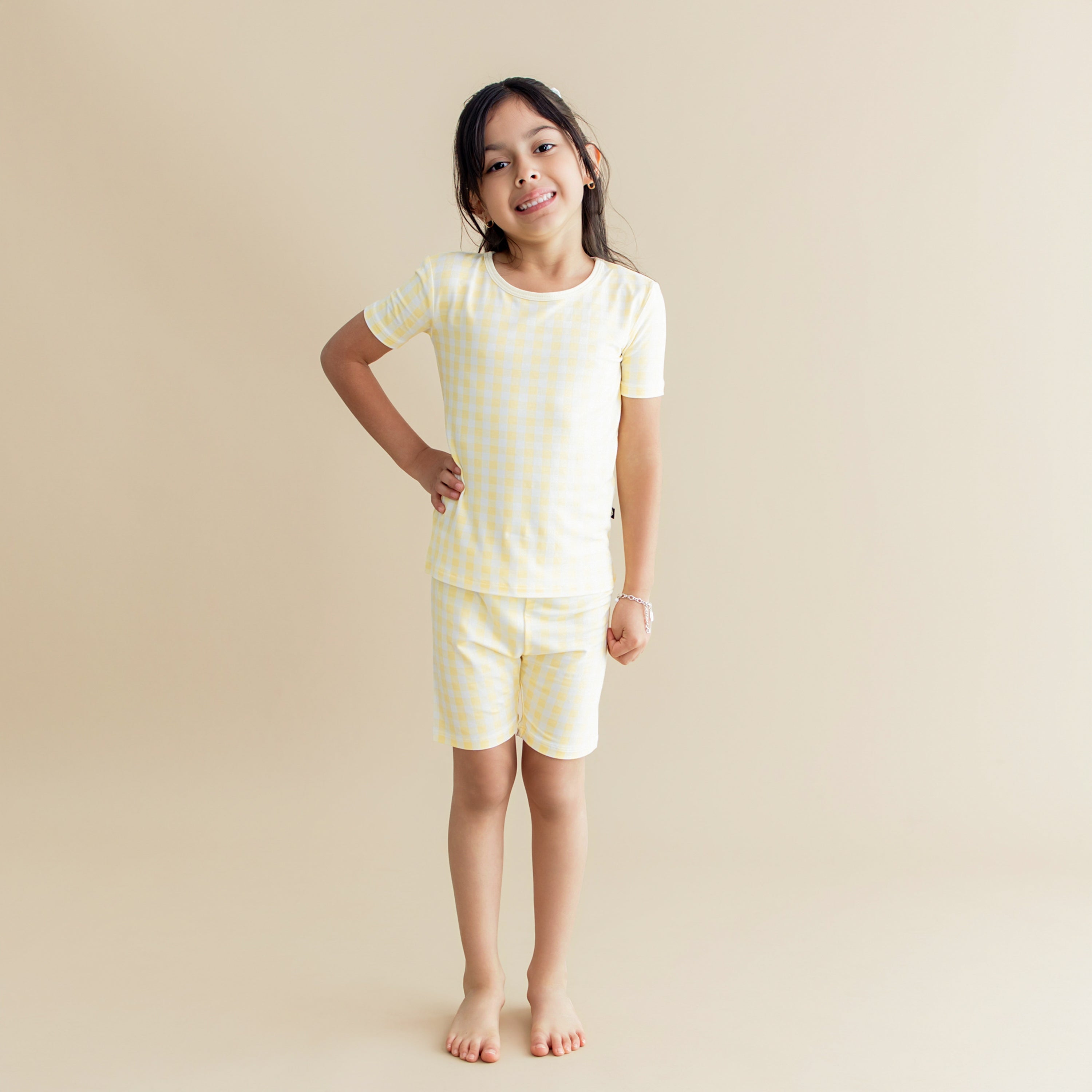 Young girl standing posing with one arm on his hip wearing the Short Sleeve Pajamas in Gingham Chamomile