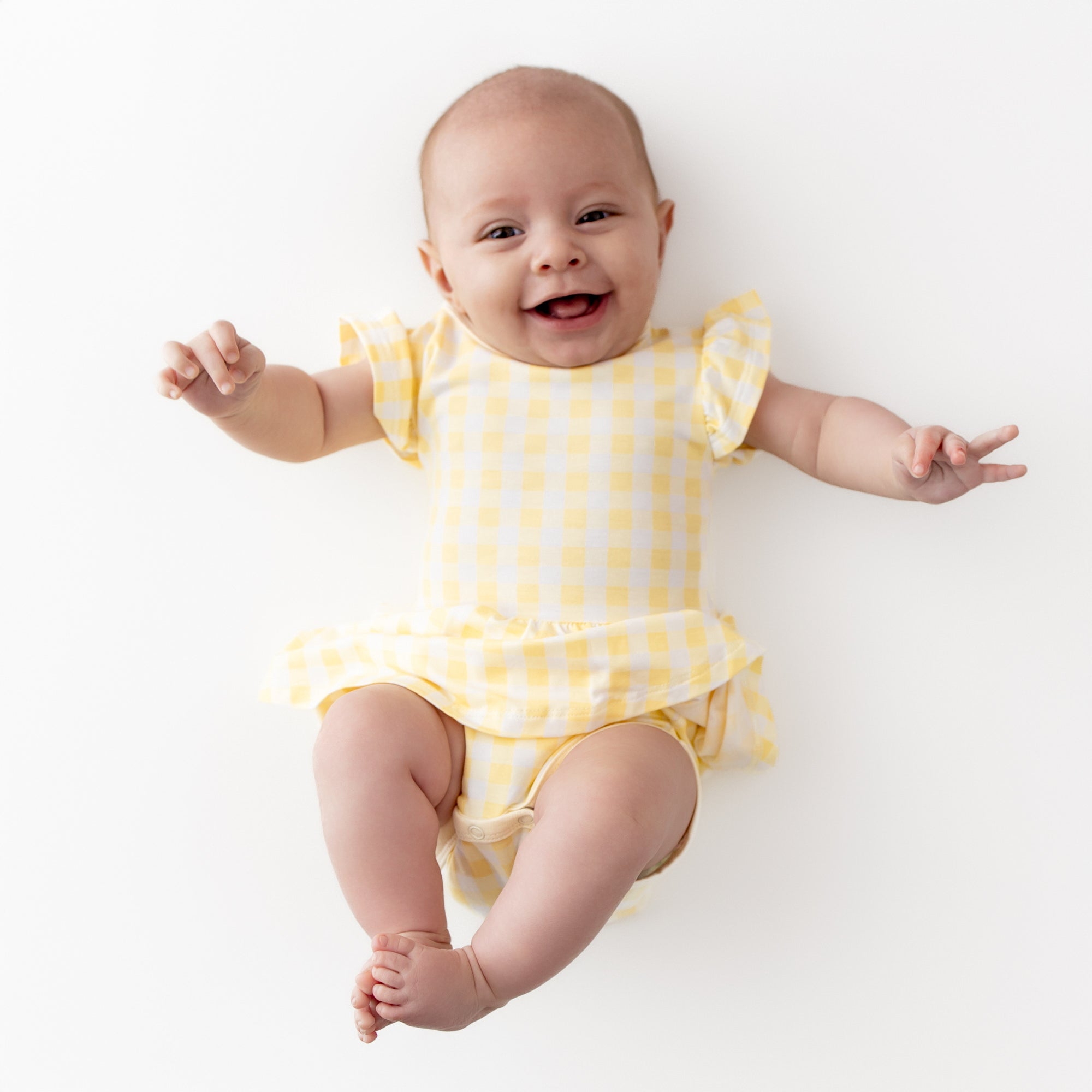 Smiling girl wearing the Twirl Bodysuit Dress in Gingham Chamomile
