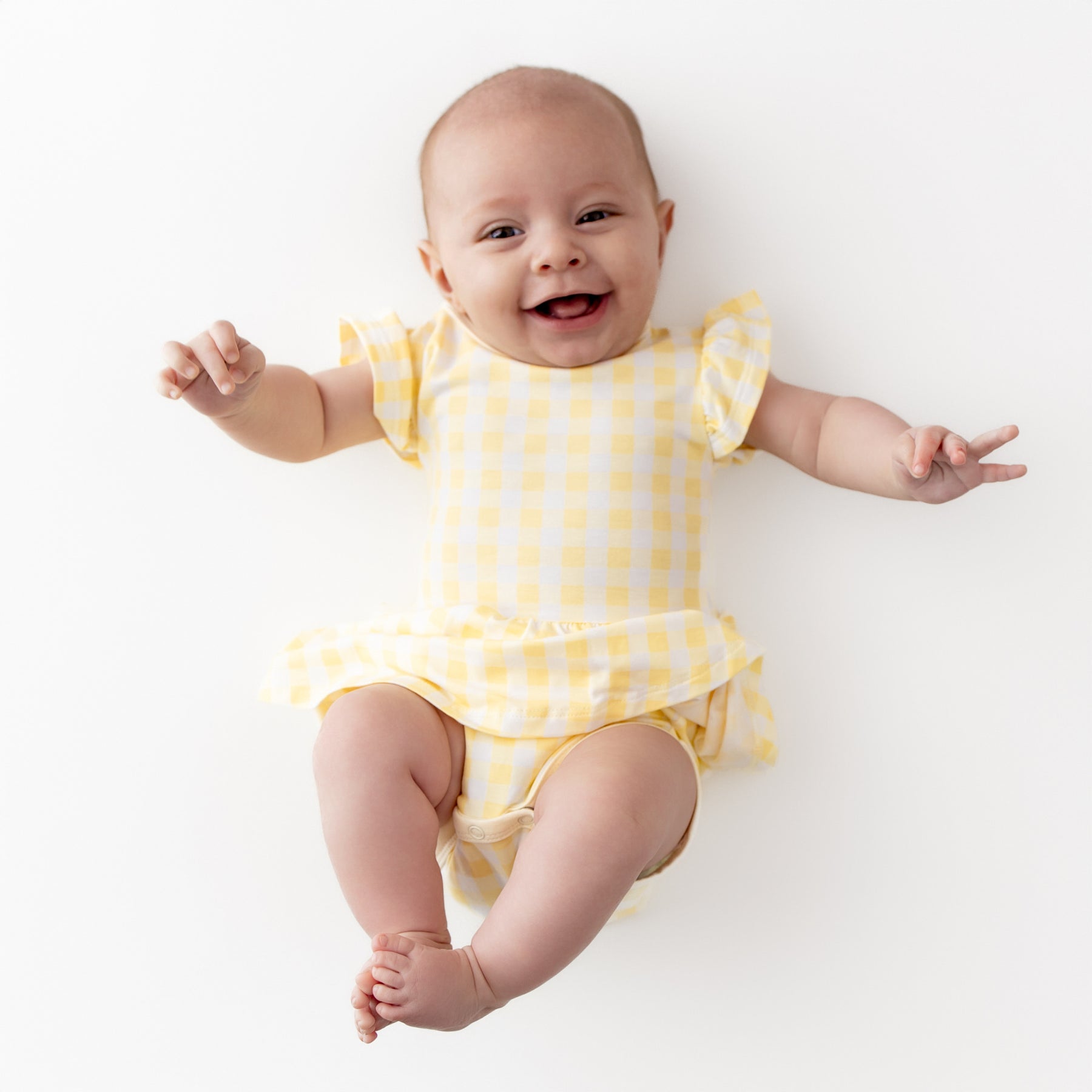 Smiling girl wearing the Twirl Bodysuit Dress in Gingham Chamomile