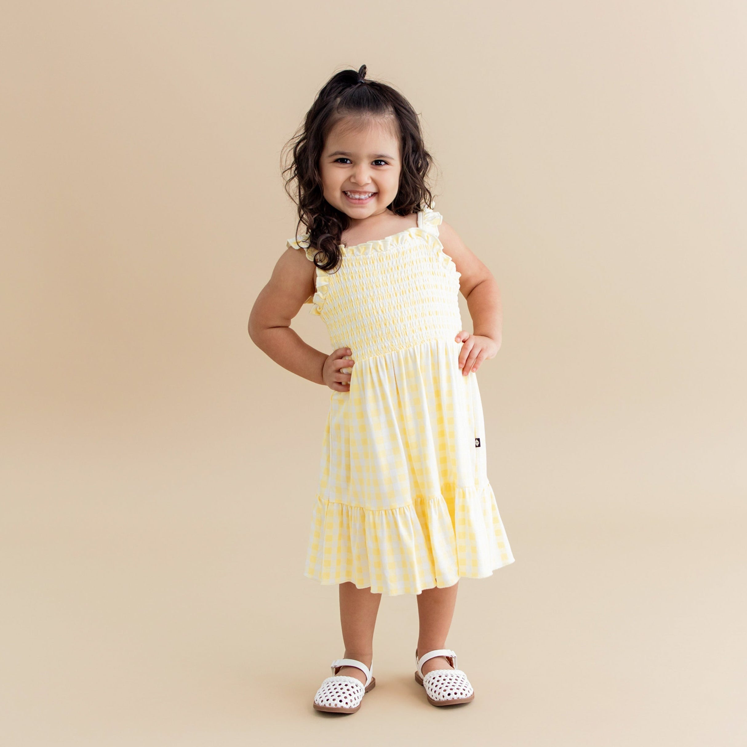 Young girl posing wearing the Smocked Dress in Gingham Chamomile