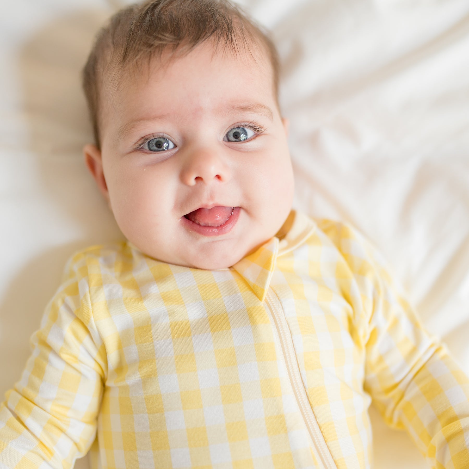 Close up of infant wearing the Zippered Footie in Gingham Chamomile