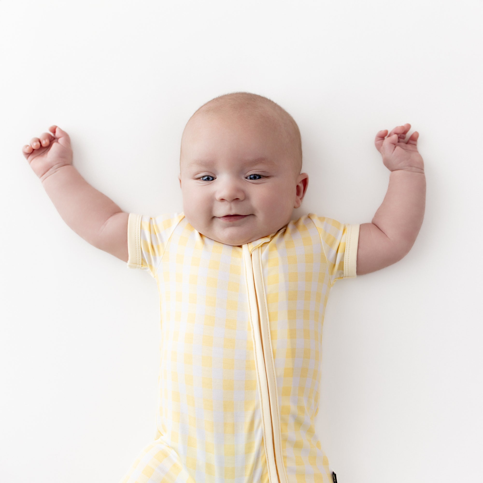 Close up of infant wearing the Zipper Shortall Romper in Gingham Chamomile
