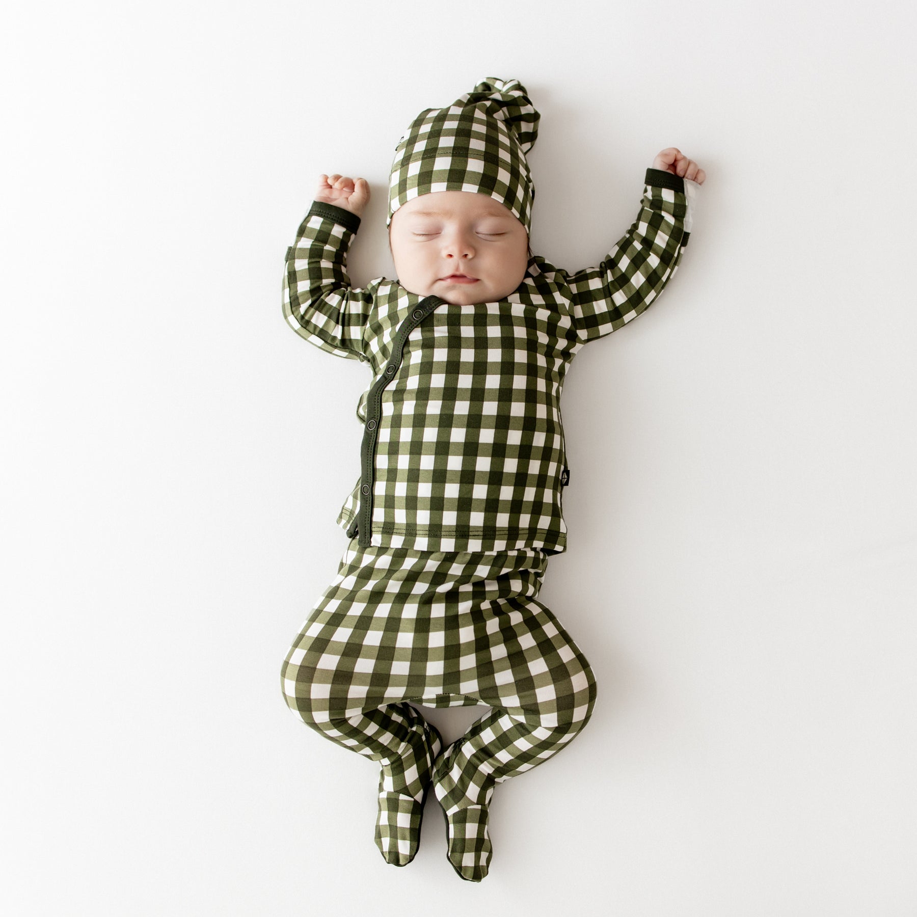 Sleeping infant laying down wearing the Take Me Home Set with Cap in Gingham Fir
