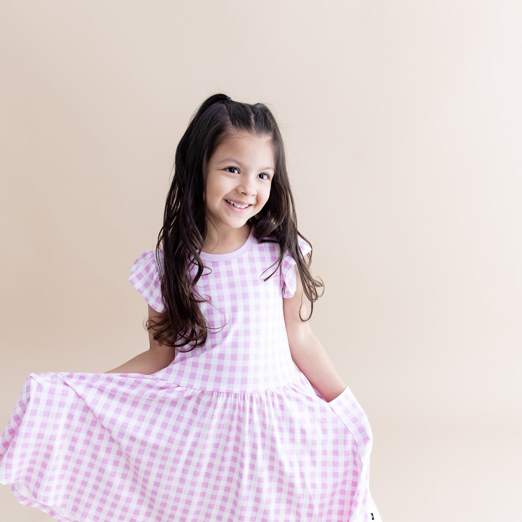Close up of a young girl wearing the Pocket Dress in Gingham Thistle with her hands in the pocket of the dress