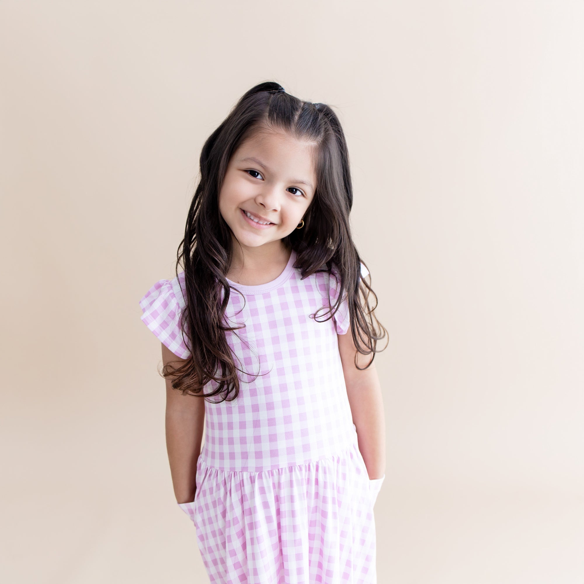 Smiling girl posing wearing the Pocket Dress in Gingham Thistle with her hands in the pockets