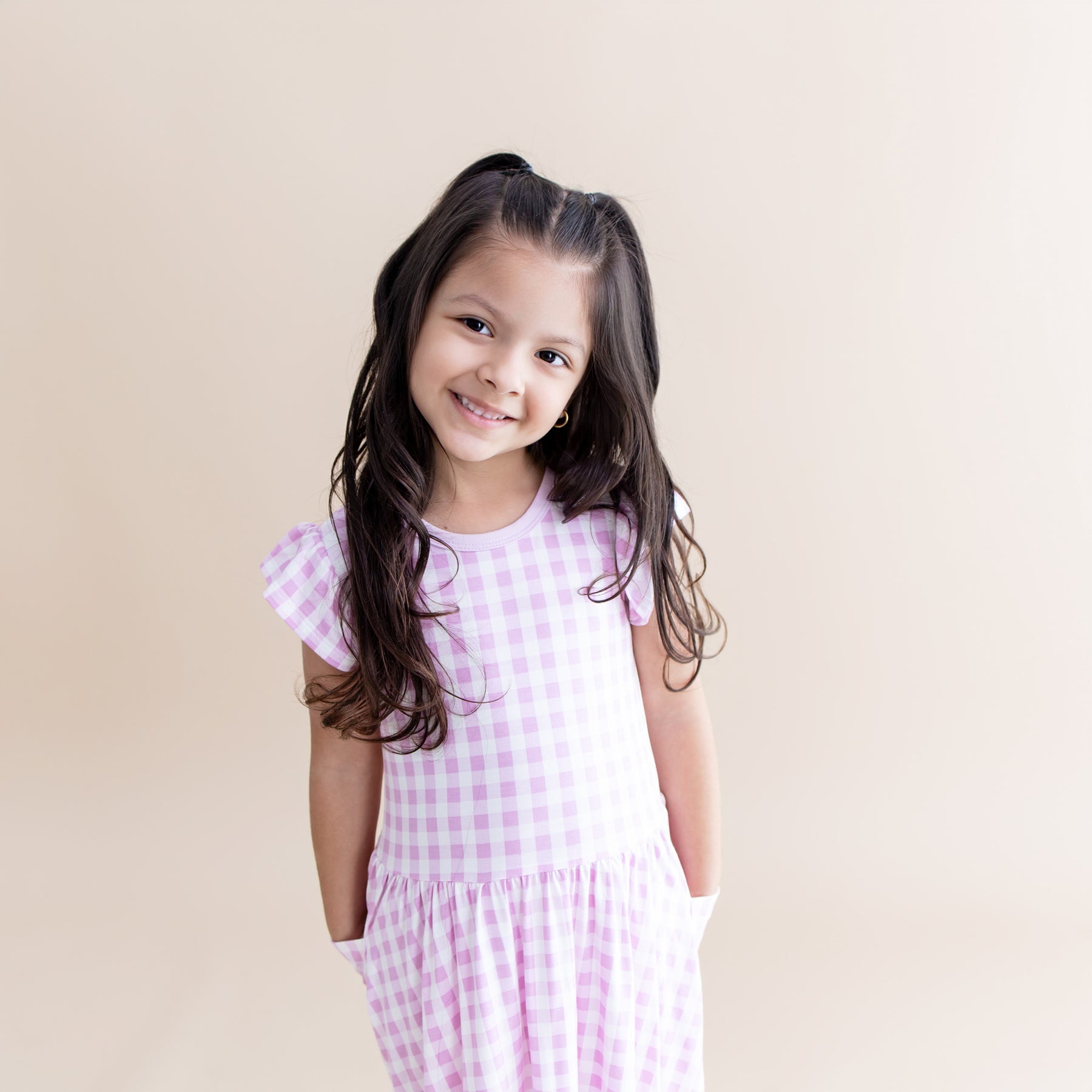 Smiling girl posing wearing the Pocket Dress in Gingham Thistle with her hands in the pockets