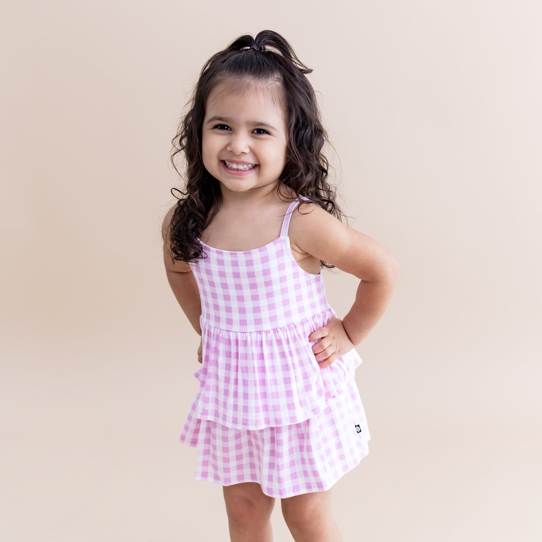 Smiling toddler posing wearing the Spaghetti Strap Ruffle Romper in Gingham Thistle