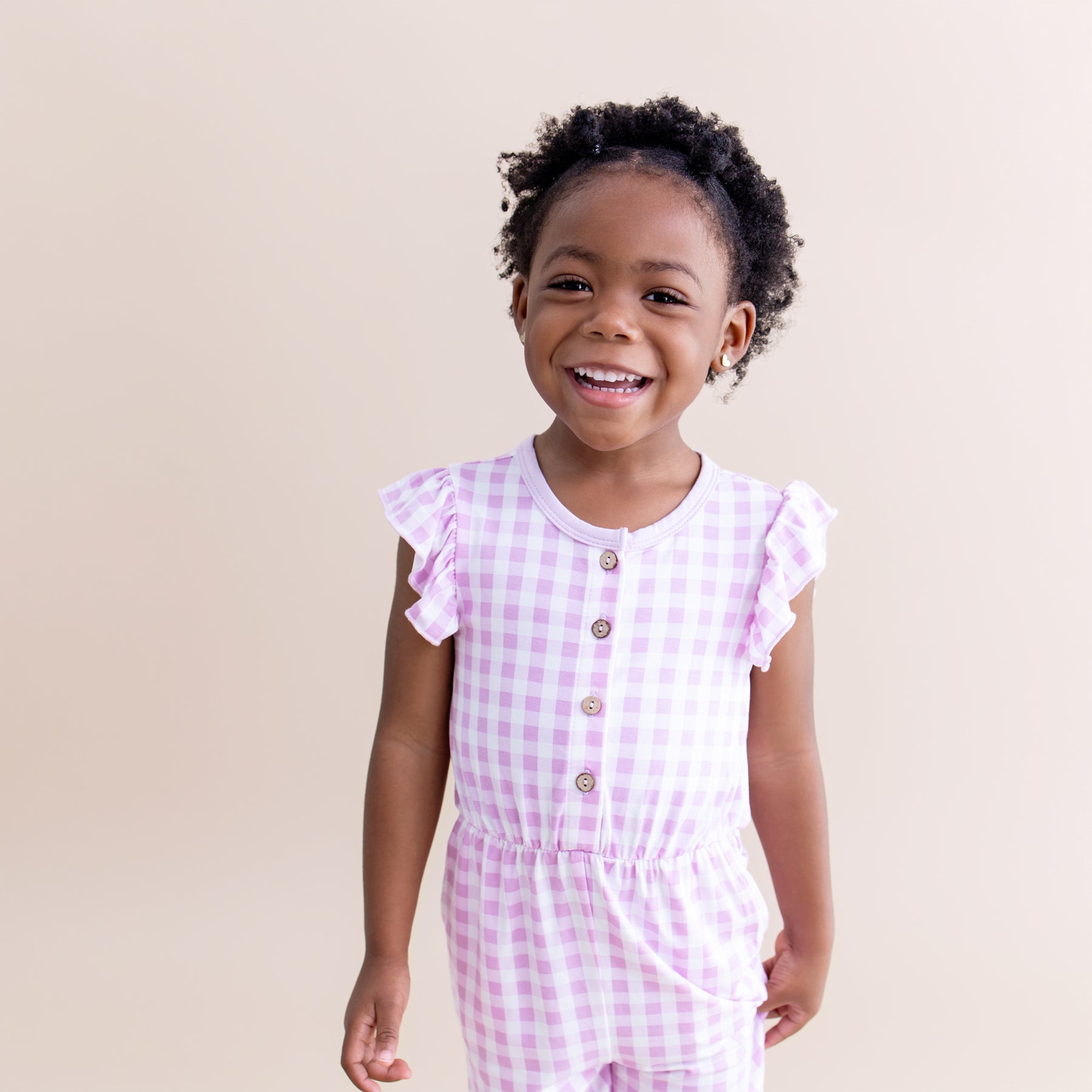 Smiling girl wearing the Flutter Sleeve Romper in Gingham Thistle
