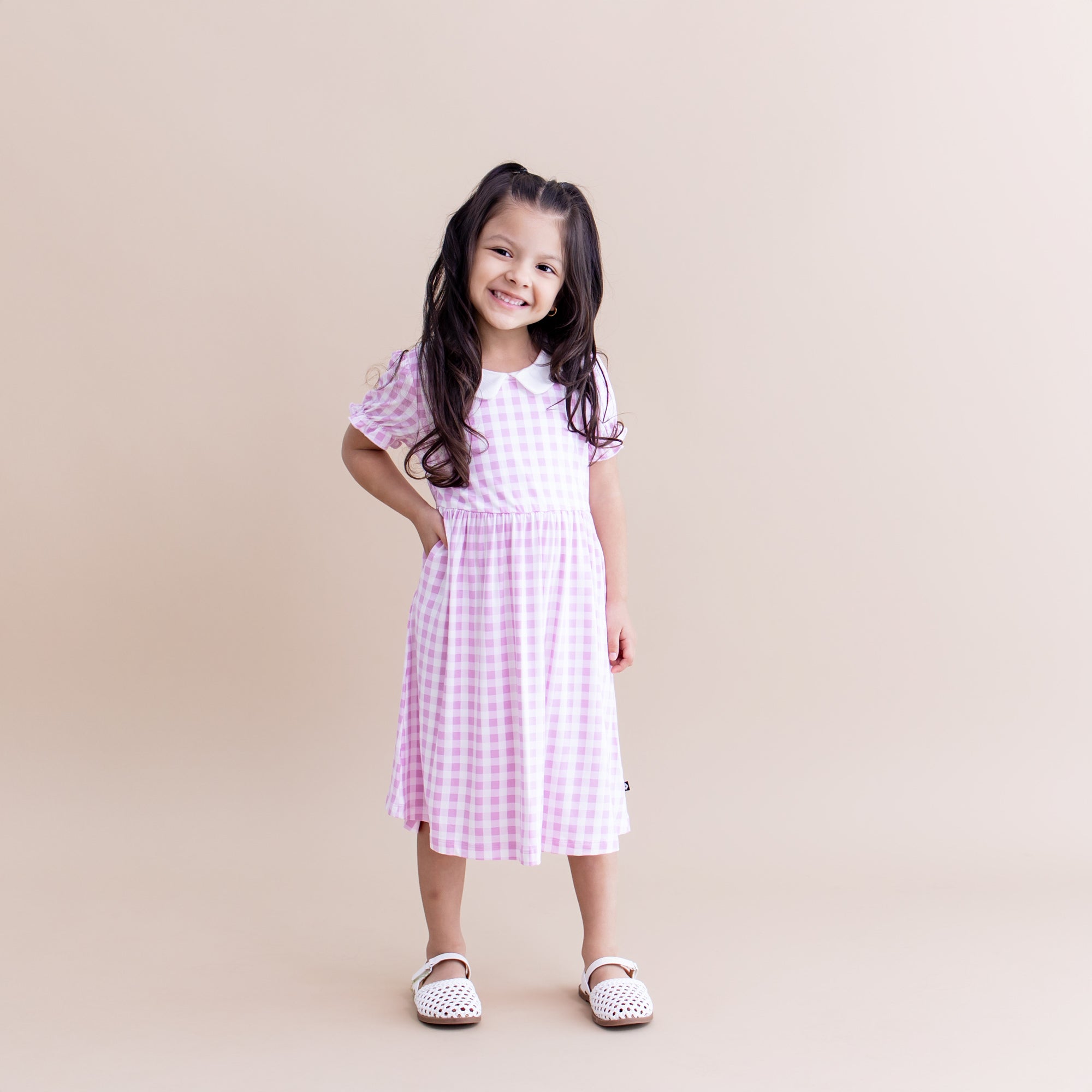 Young smiling girl posing wearing the Peter Pan Collar Dress in Gingham Thistle with white sandals