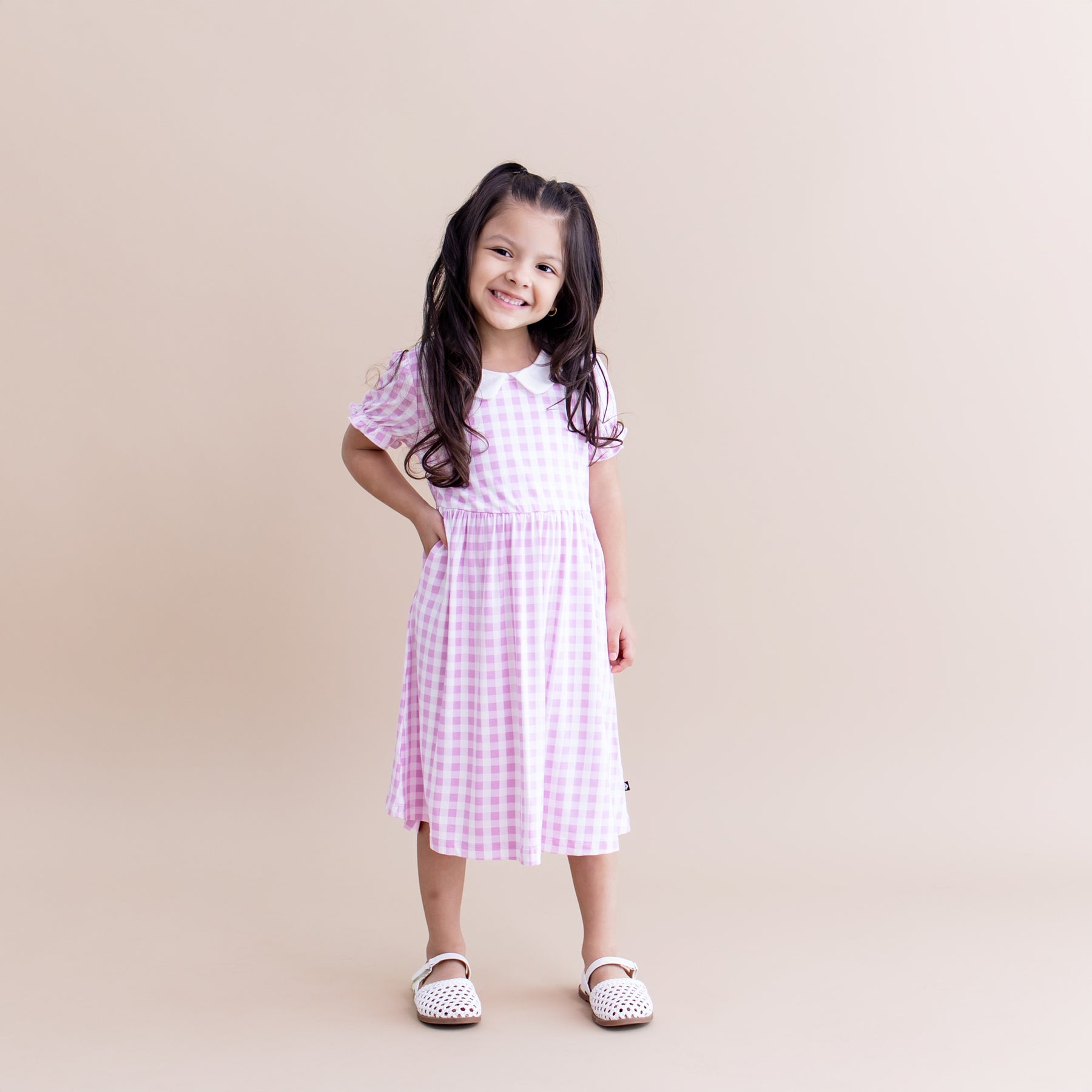 Young smiling girl posing wearing the Peter Pan Collar Dress in Gingham Thistle with white sandals