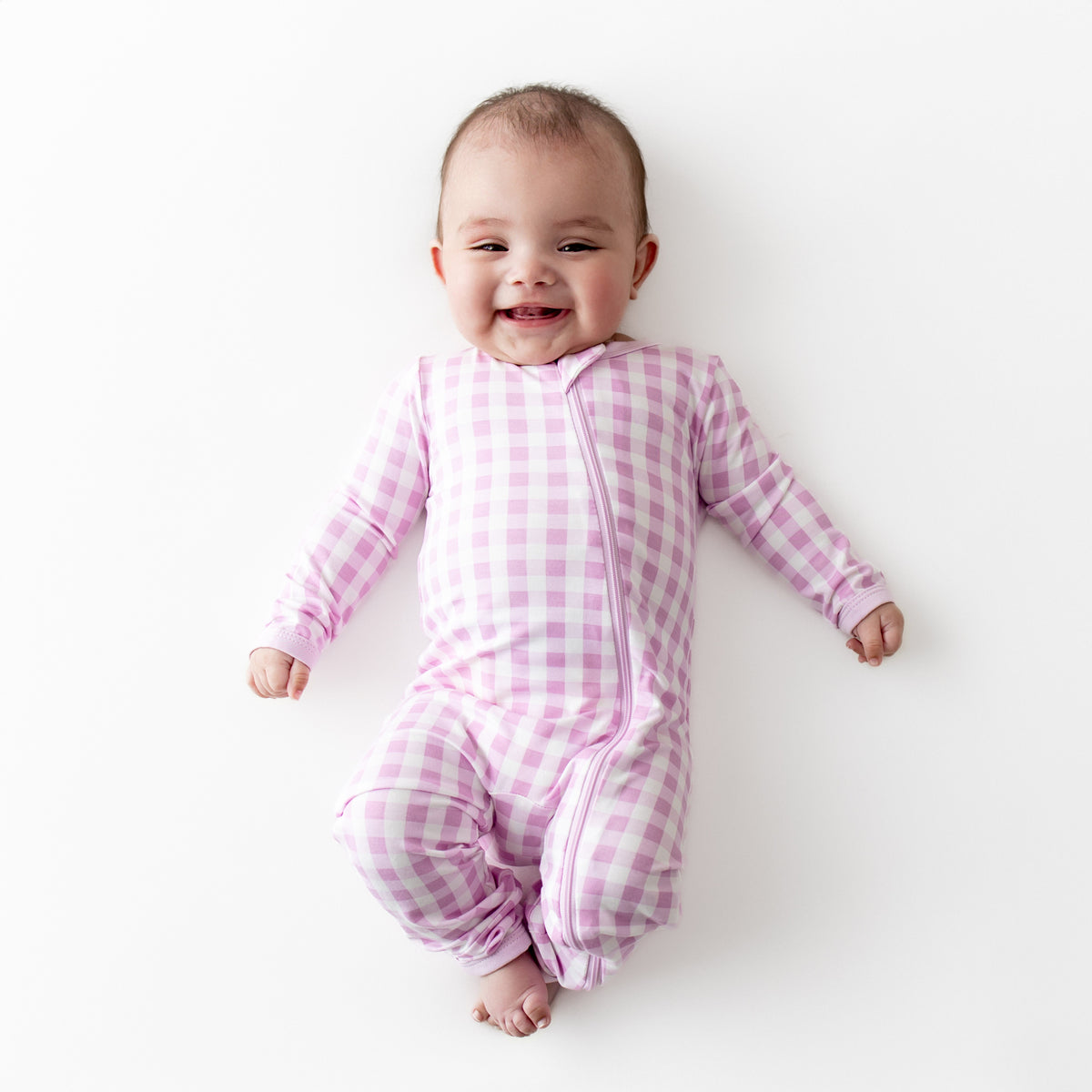 Smiling infant wearing the Zippered Romper in Gingham Thistle