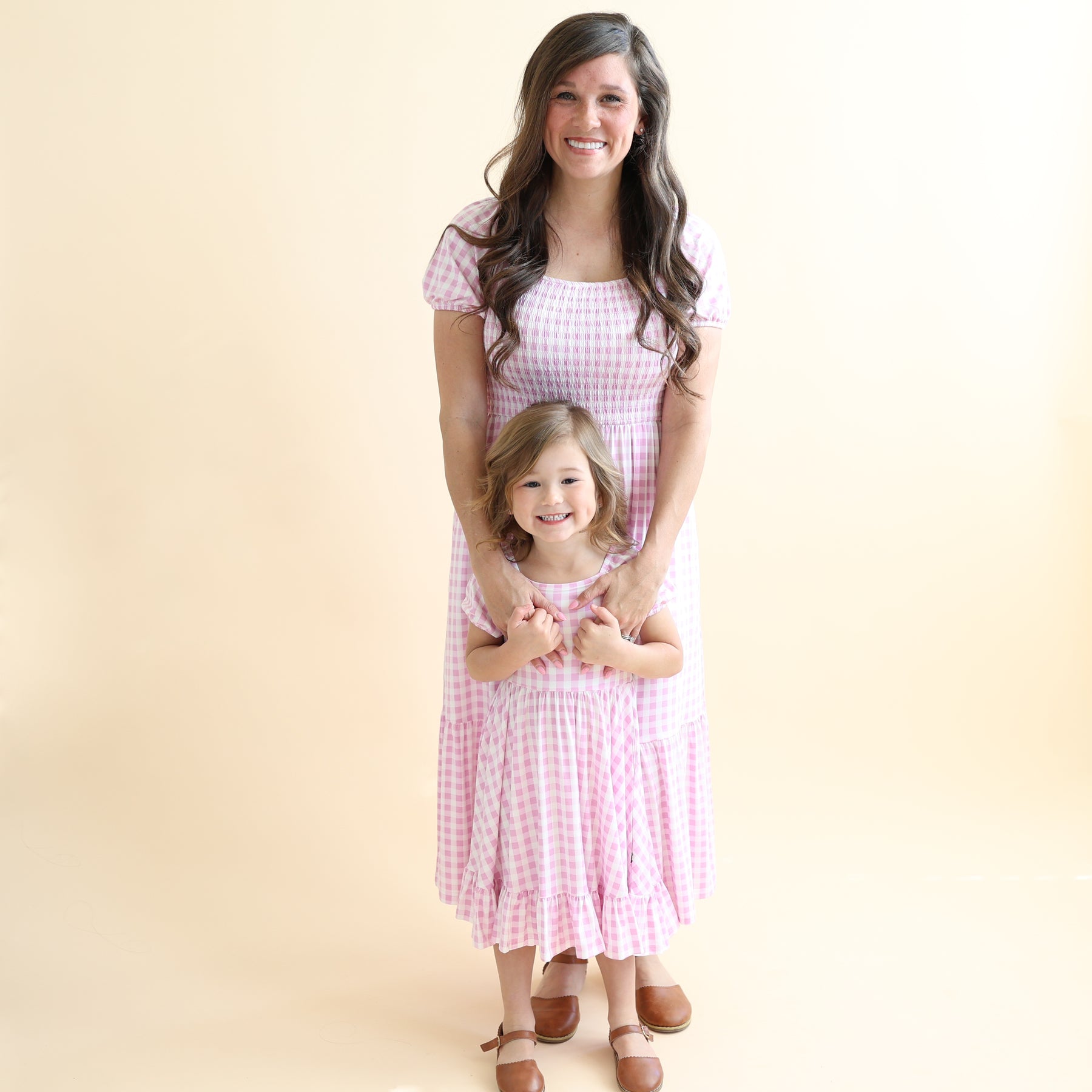 Mother and daughter matching wearing the Smocked Dress and Puff Sleeve Twirl Dress in Gingham Thistle