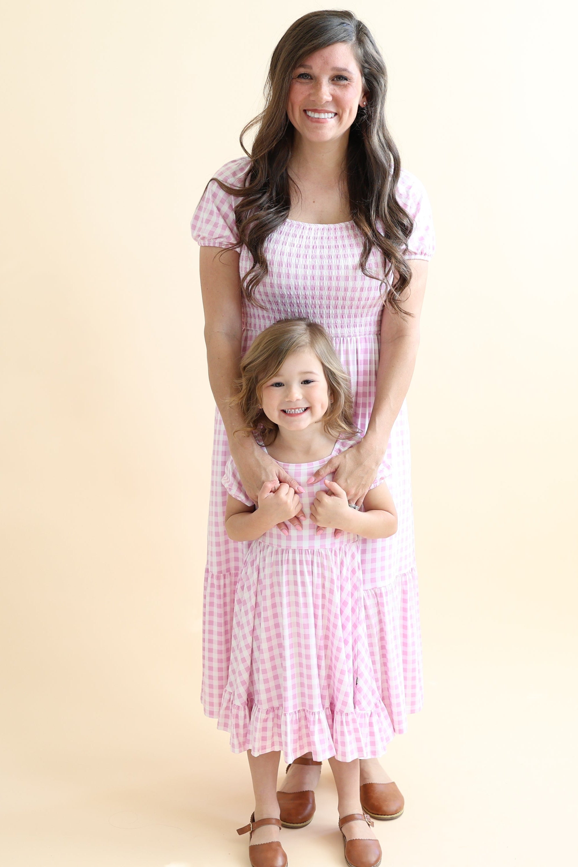 Mother and daughter matching wearing the Women’s Smocked Dress in Gingham Thistle and puff sleeve twirl dress