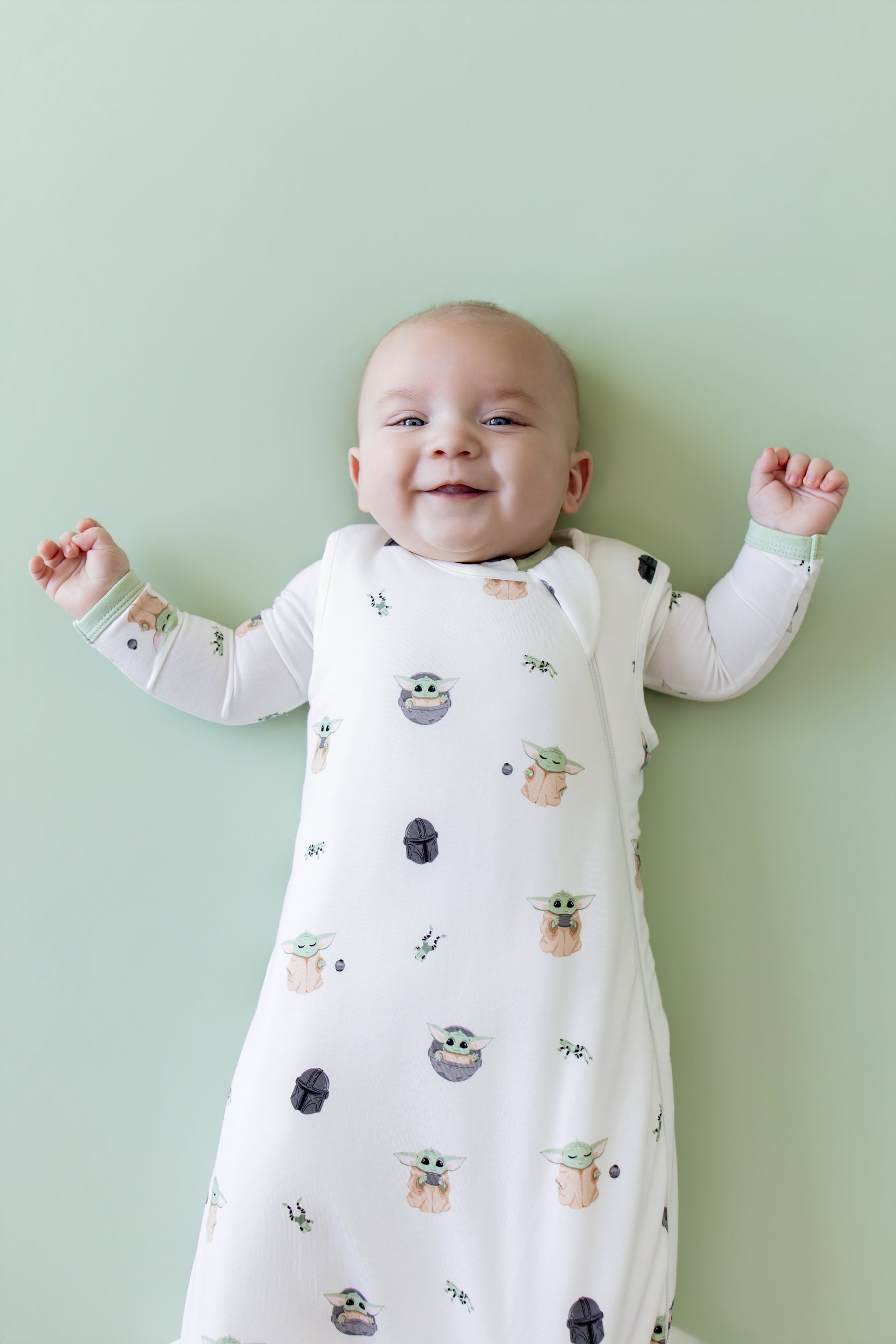 Close up of smiling infant wearing the Sleep Bag in Grogu™ 1.0 with matching romper on underneath