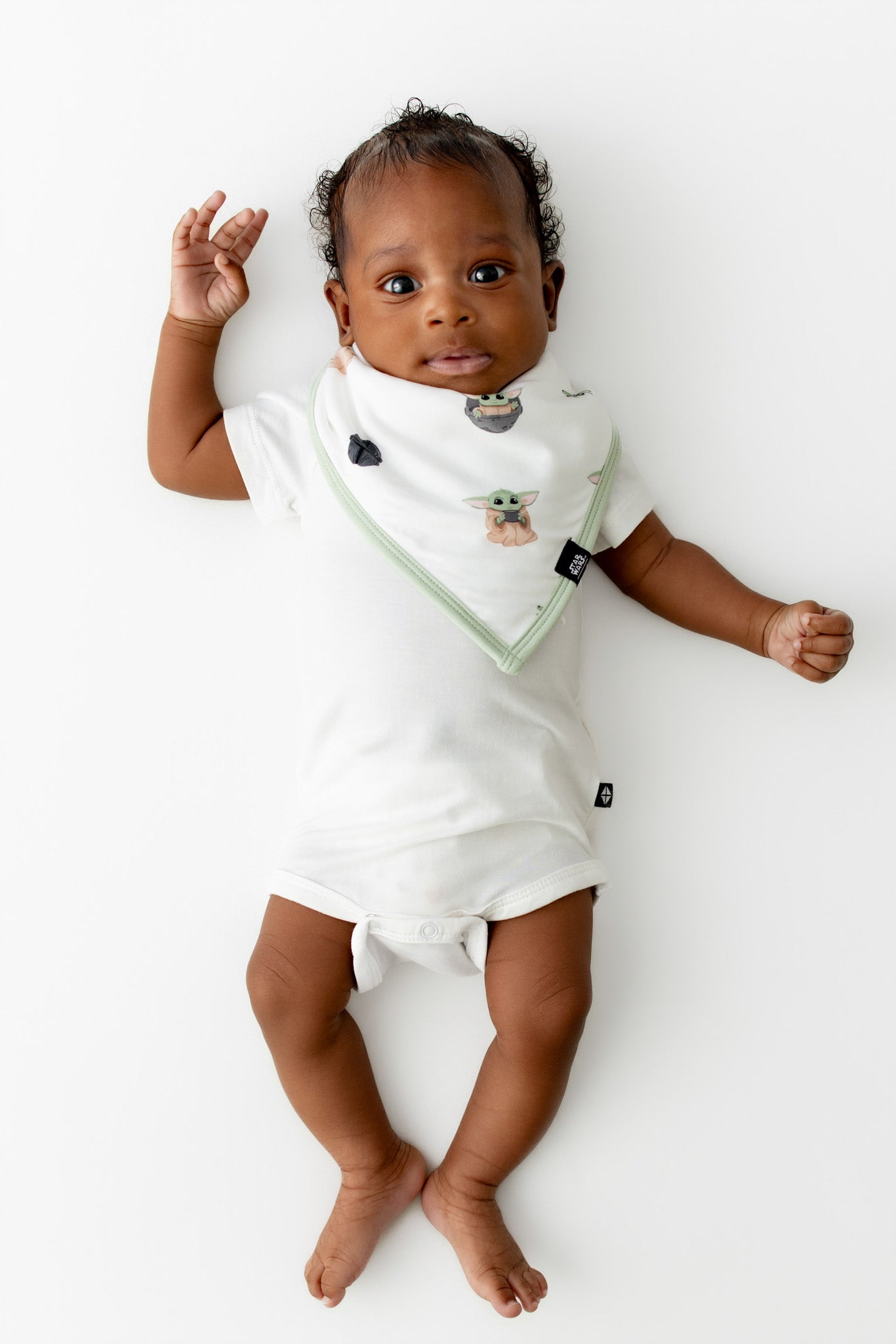 Infant laying on a white surface wearing the Bib in Grogu™ with a short sleeve bodysuit