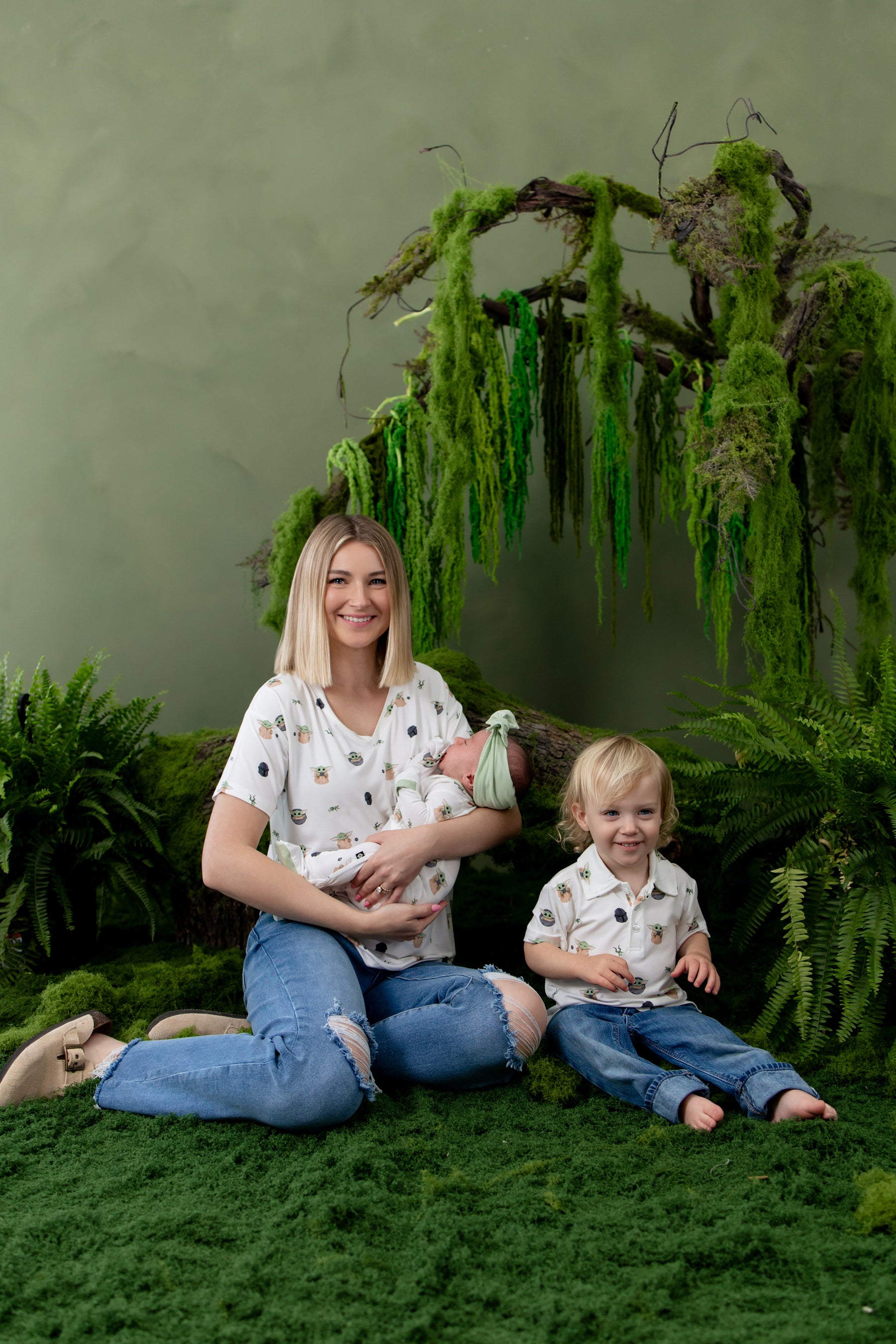 Family of three sitting on greenery wearing various items in Grogu™