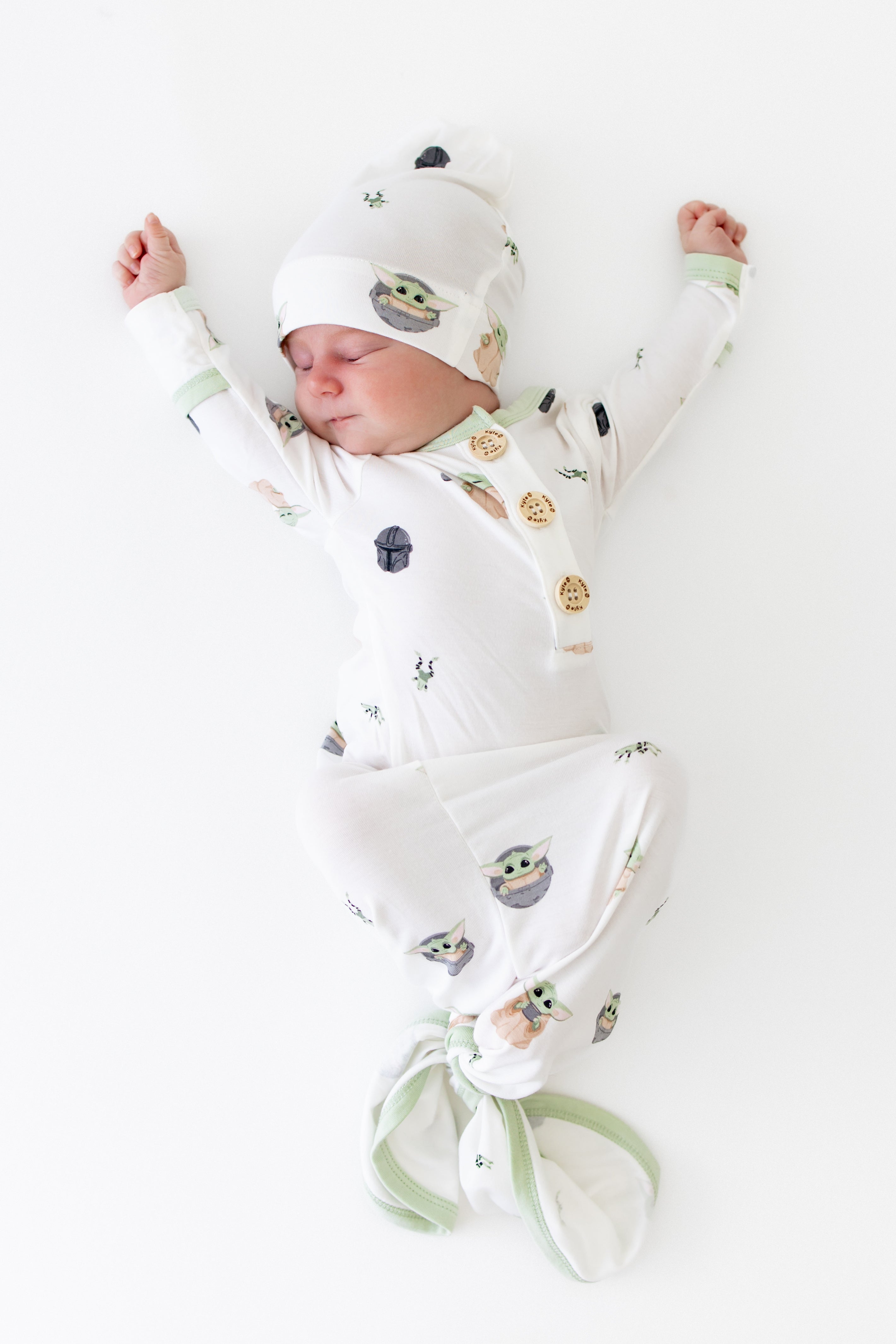 Newborn stretching wearing the Knotted Gown with Hat Set in Grogu™