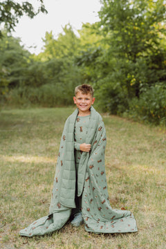 Boy outside with groot blanket over his shoulders.