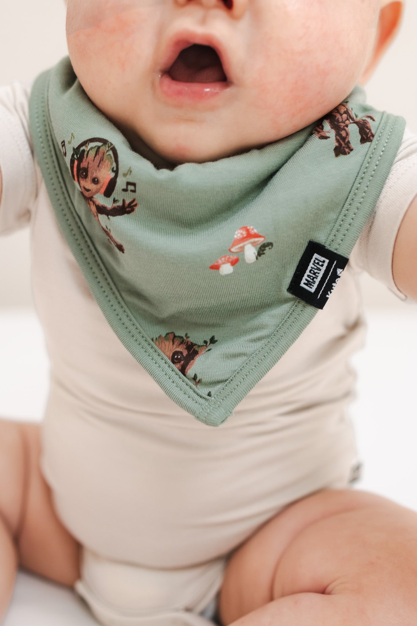 Close up of Baby wearing Green Bib in Groot print over a beige bodysuit