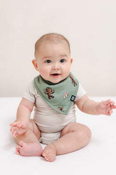 Baby wearing Green Bib in Groot print over a beige bodysuit sitting on a beige background