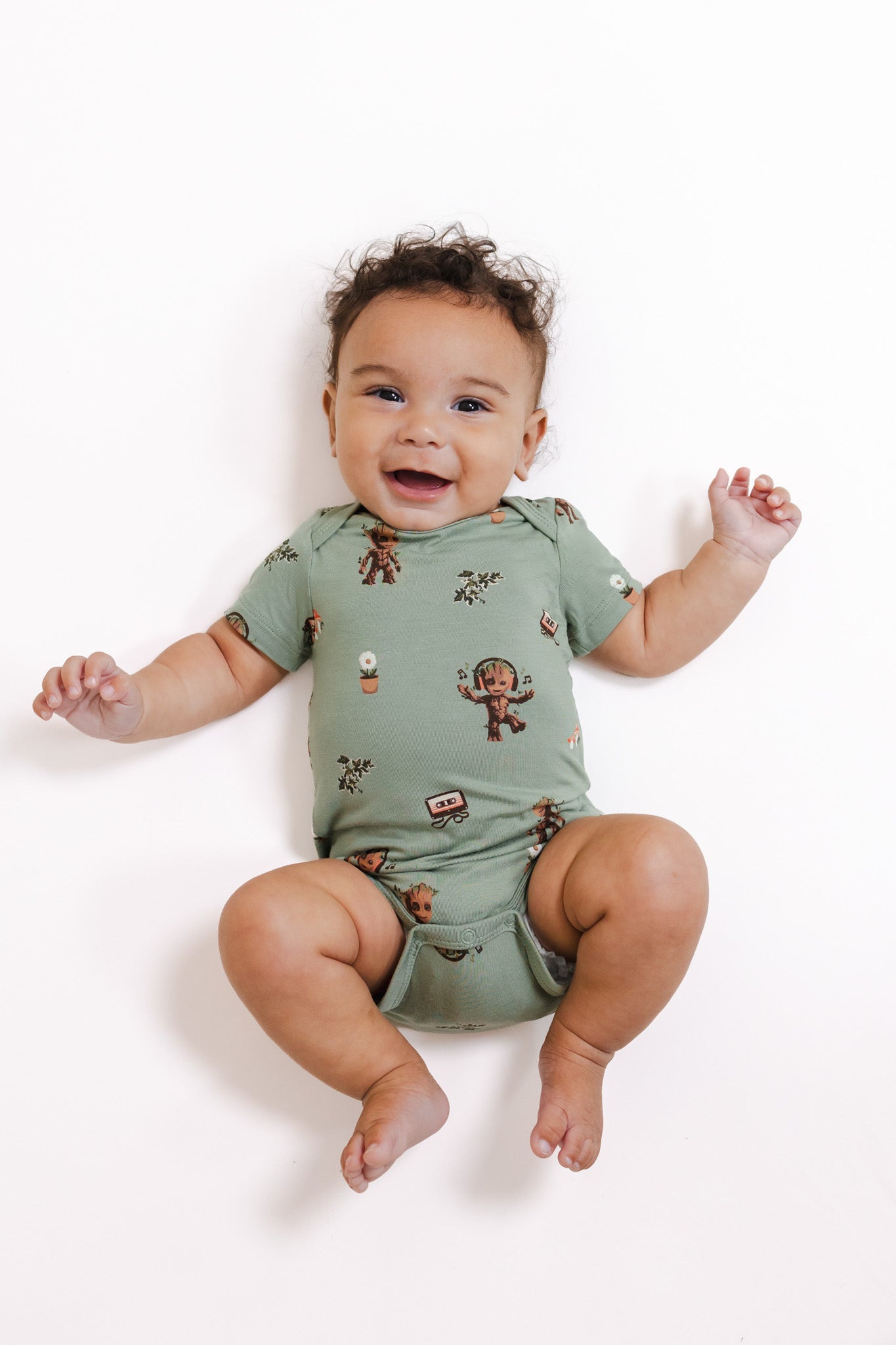 Baby wearing Green Bodysuit in Groot print lying on a white background