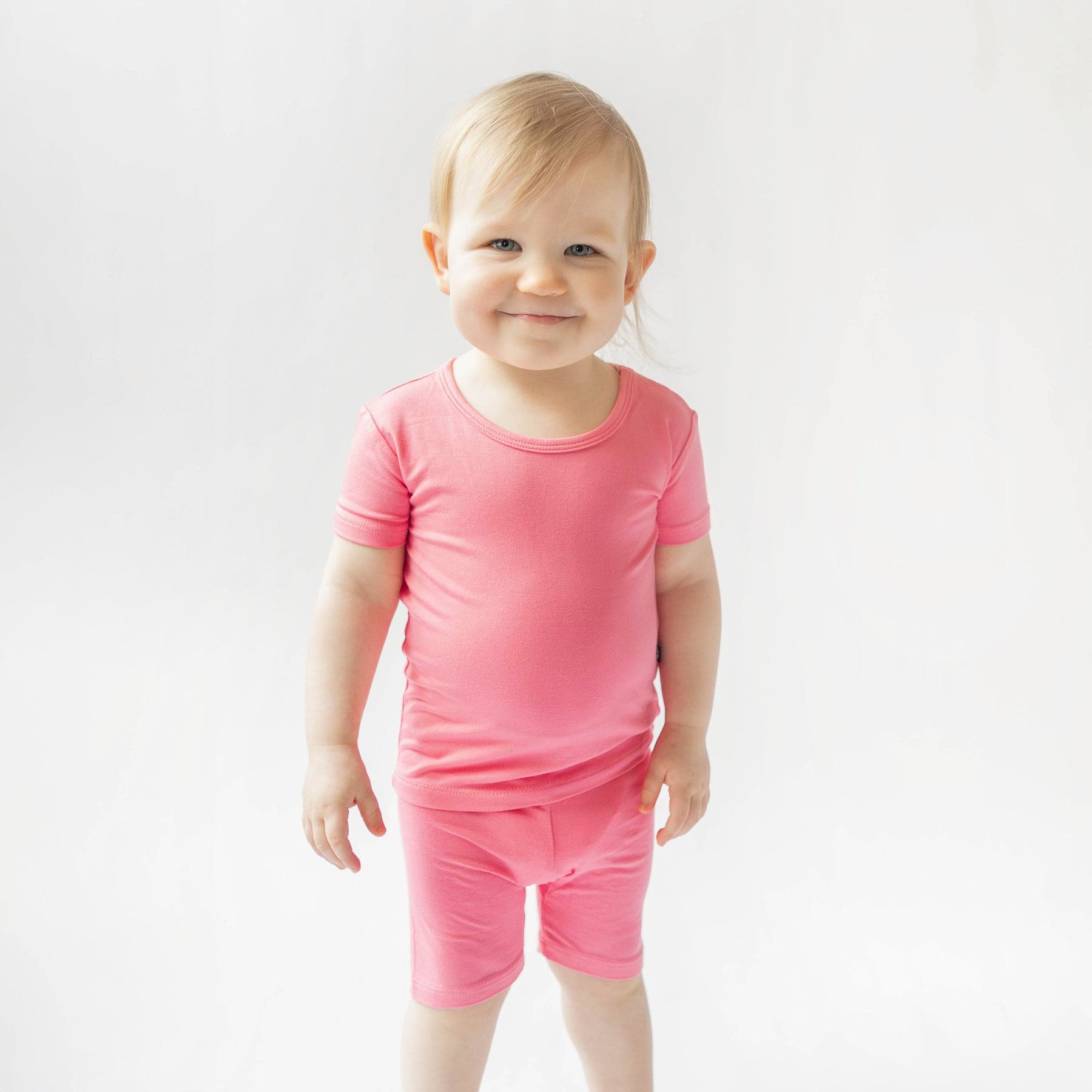 toddler wearing kyte baby short sleeve pajamas in guava 