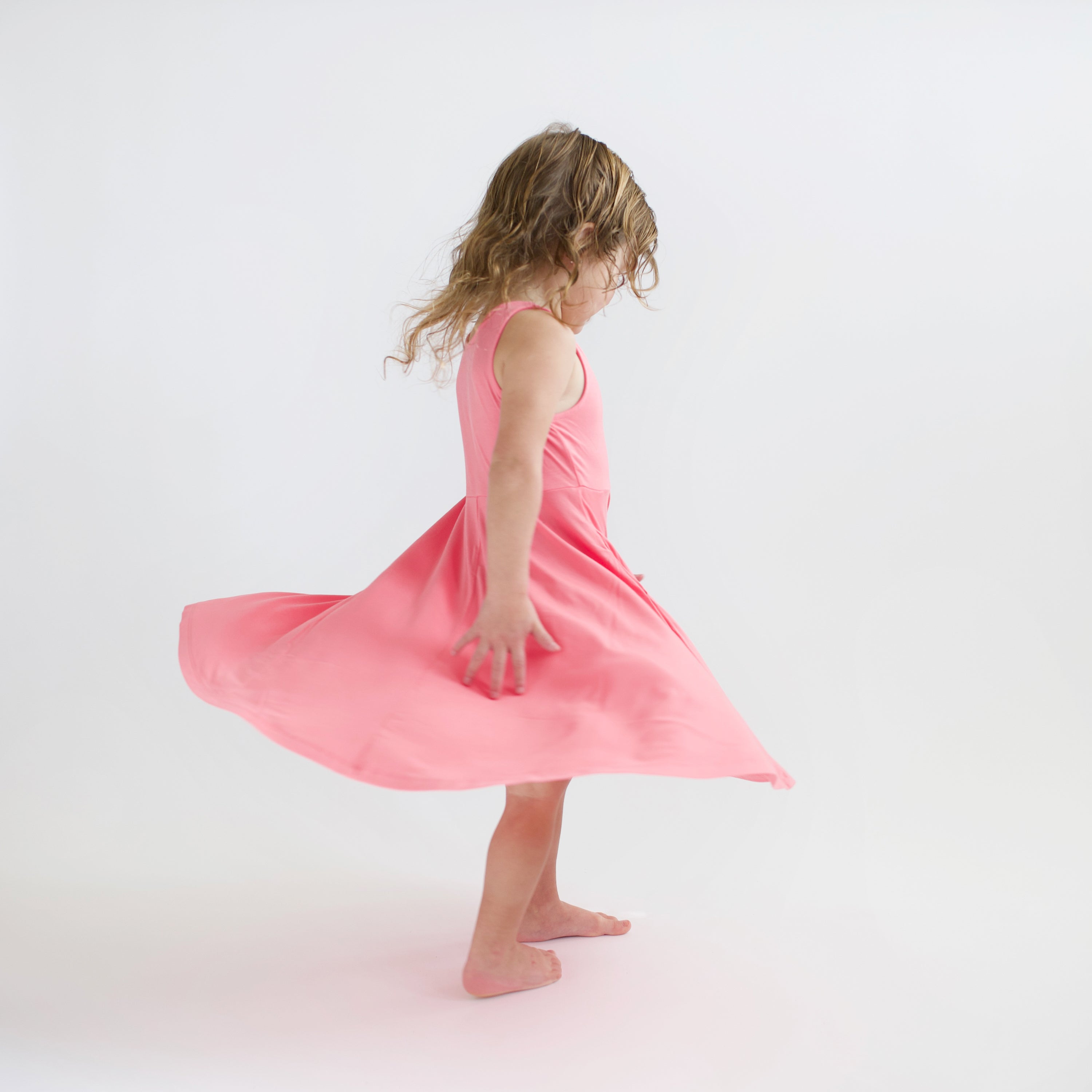 Toddler twirling in Tank Twirl Dress in Guava