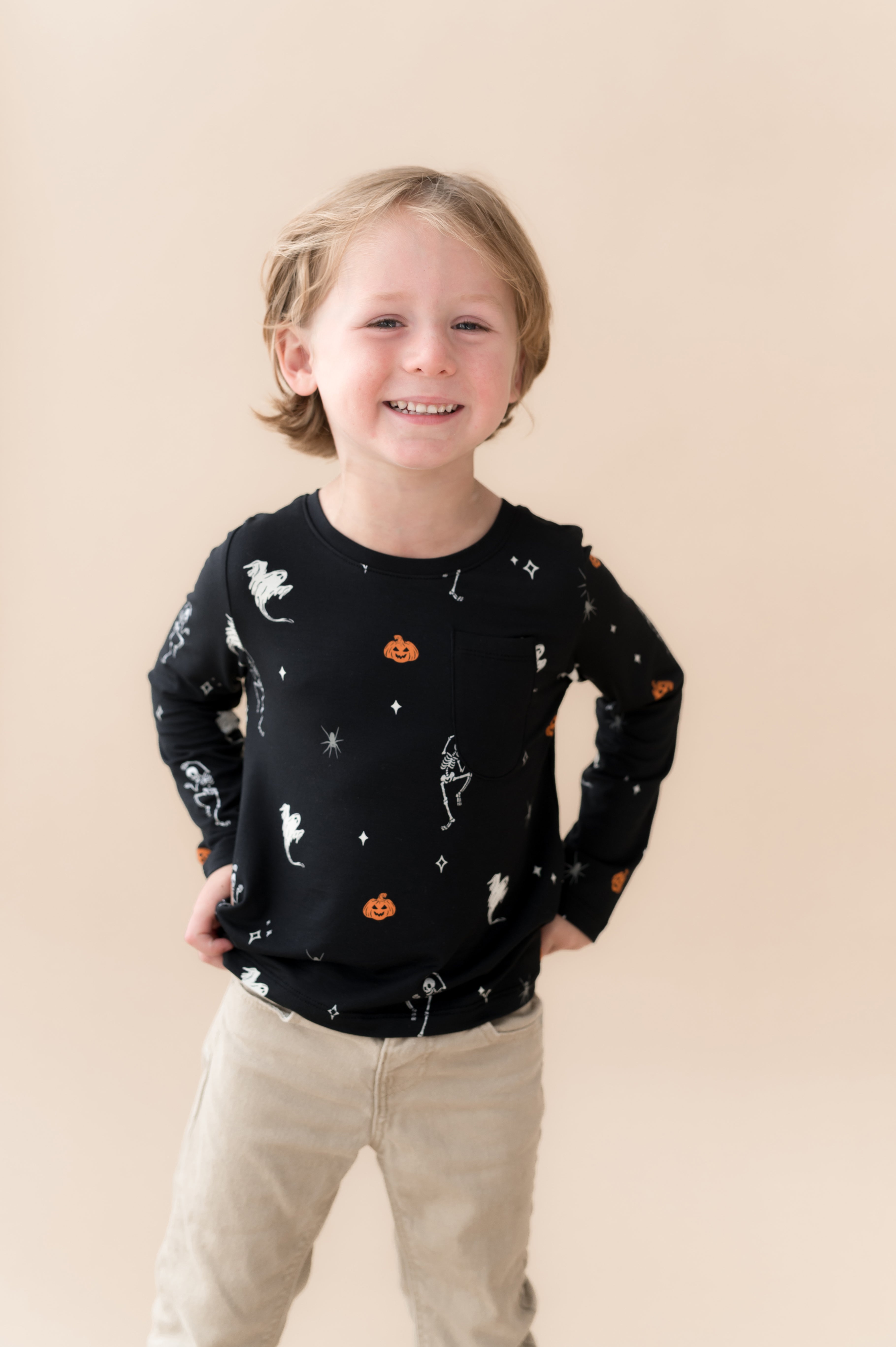 Boy wearing Long Sleeve Toddler Crew Neck Tee in Halloween Friends print over beige pants on a beige background