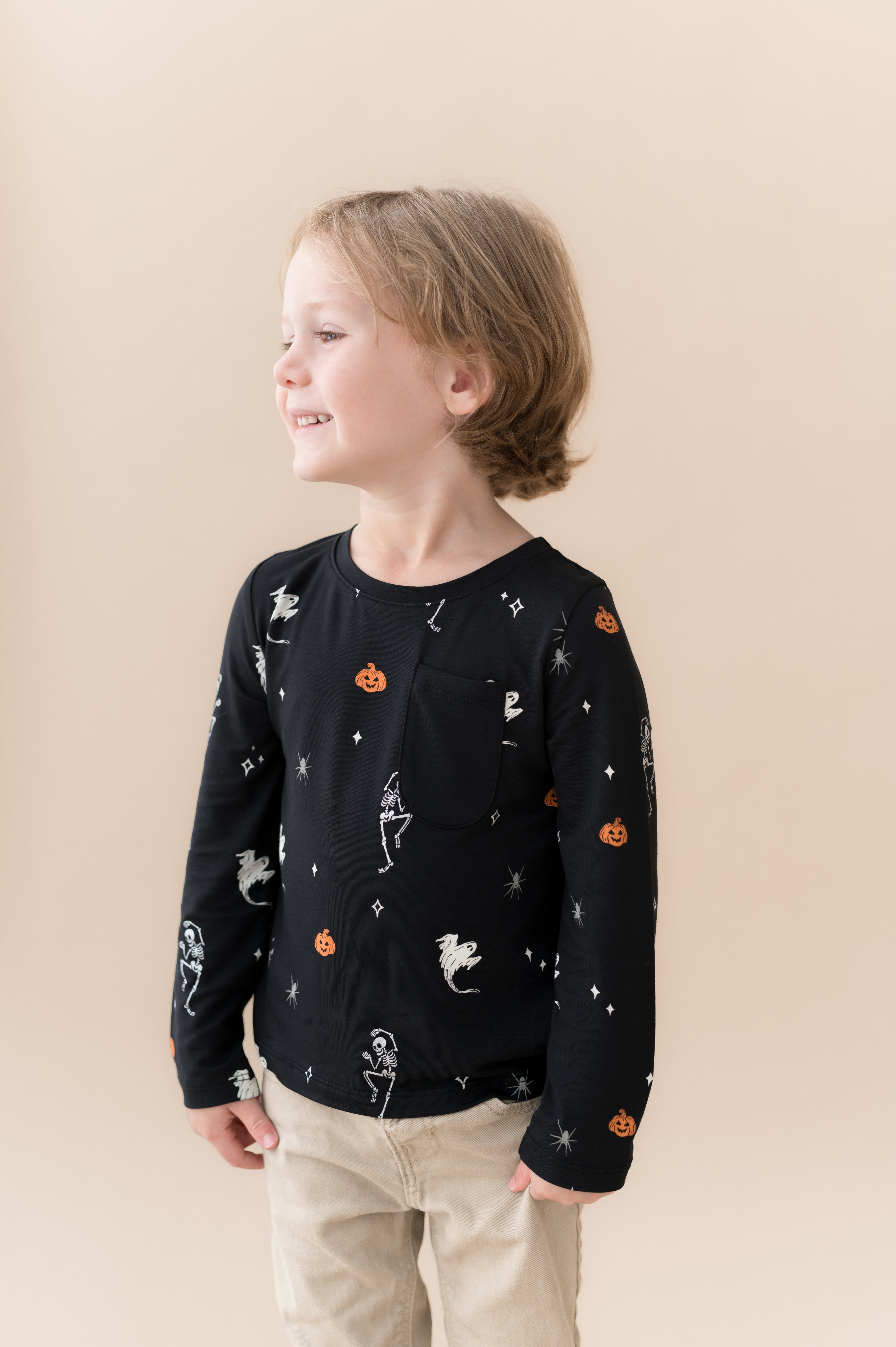 Boy posing in Long Sleeve Toddler Crew Neck Tee in Halloween Friends print over beige pants on a beige background