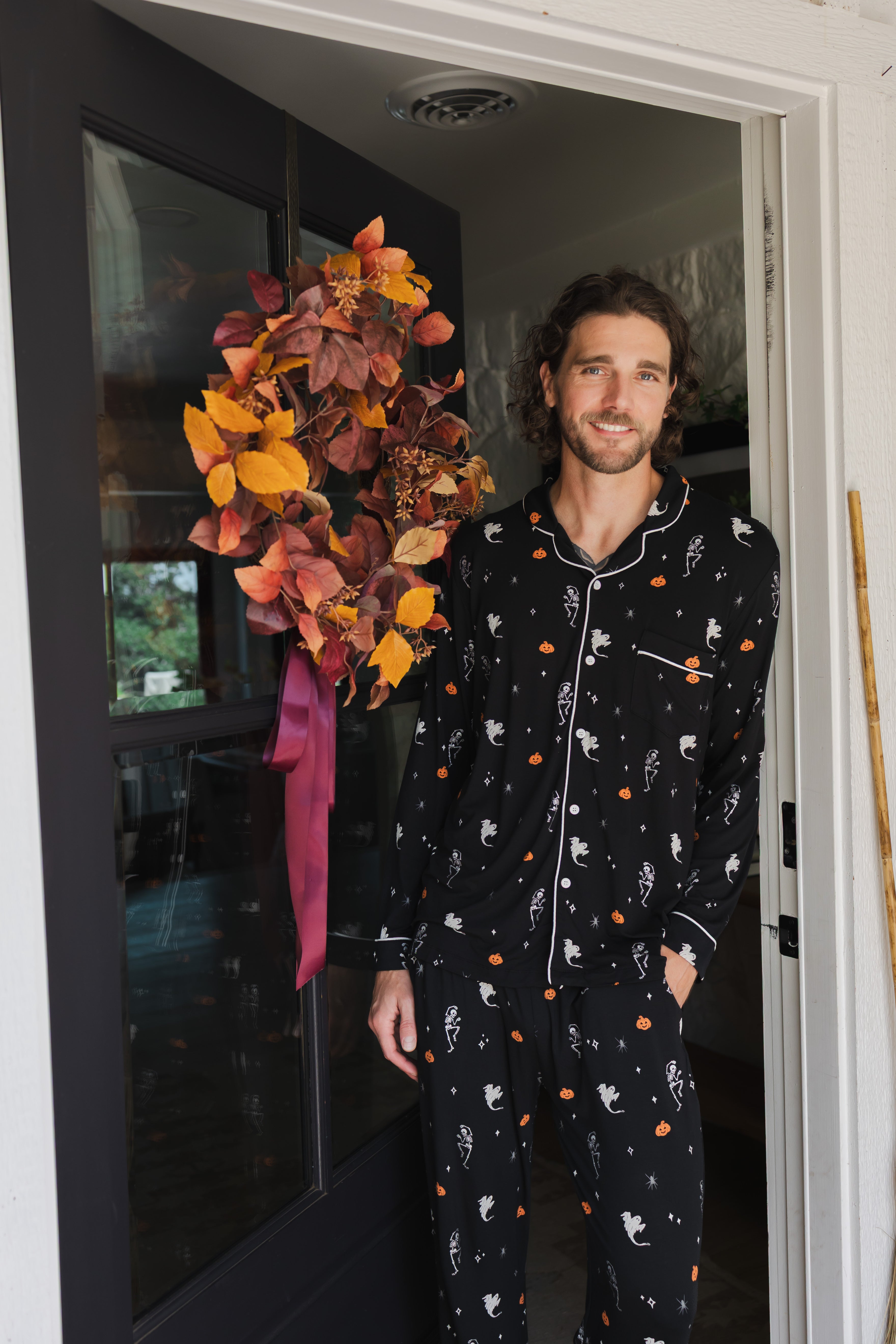 Model smiling in doorway wearing Men's Long Sleeve Pajama Set in Halloween Friends print