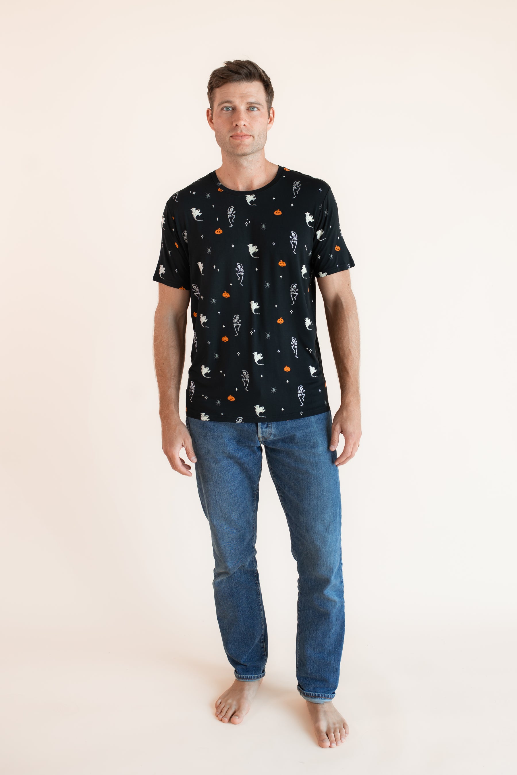 Modal wearing Men's Crew Neck Tee in Halloween Friends print over blue jeans on a beige background