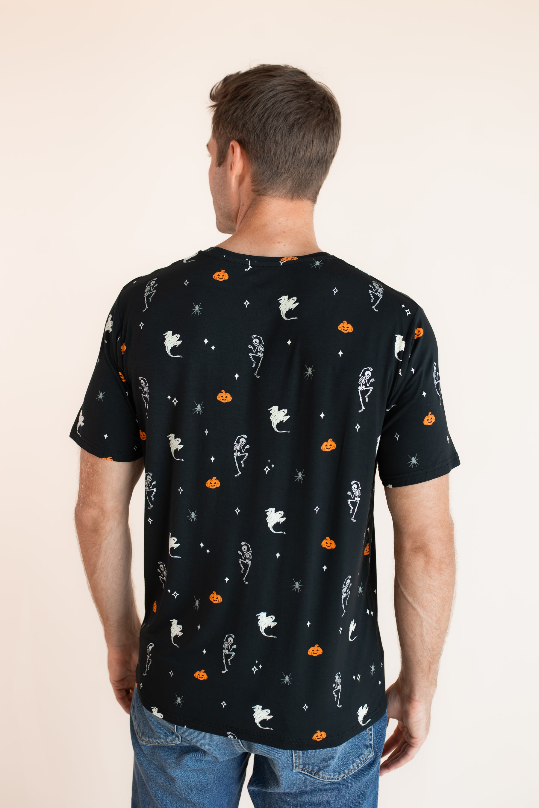 Back side of Modal wearing Men's Crew Neck Tee in Halloween Friends print over blue jeans on a beige background
