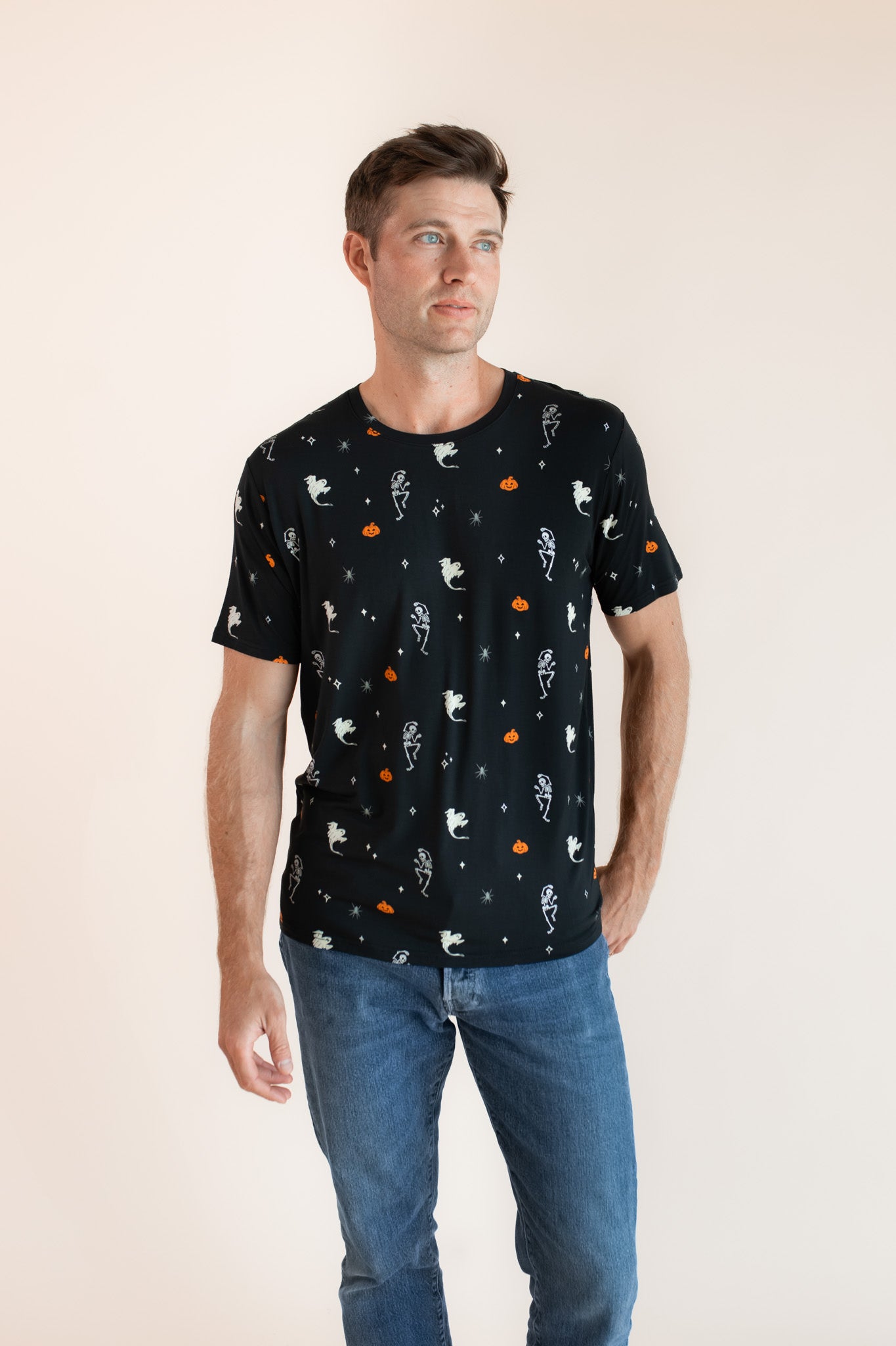 Modal posing in Men's Crew Neck Tee in Halloween Friends print over blue jeans on a beige background