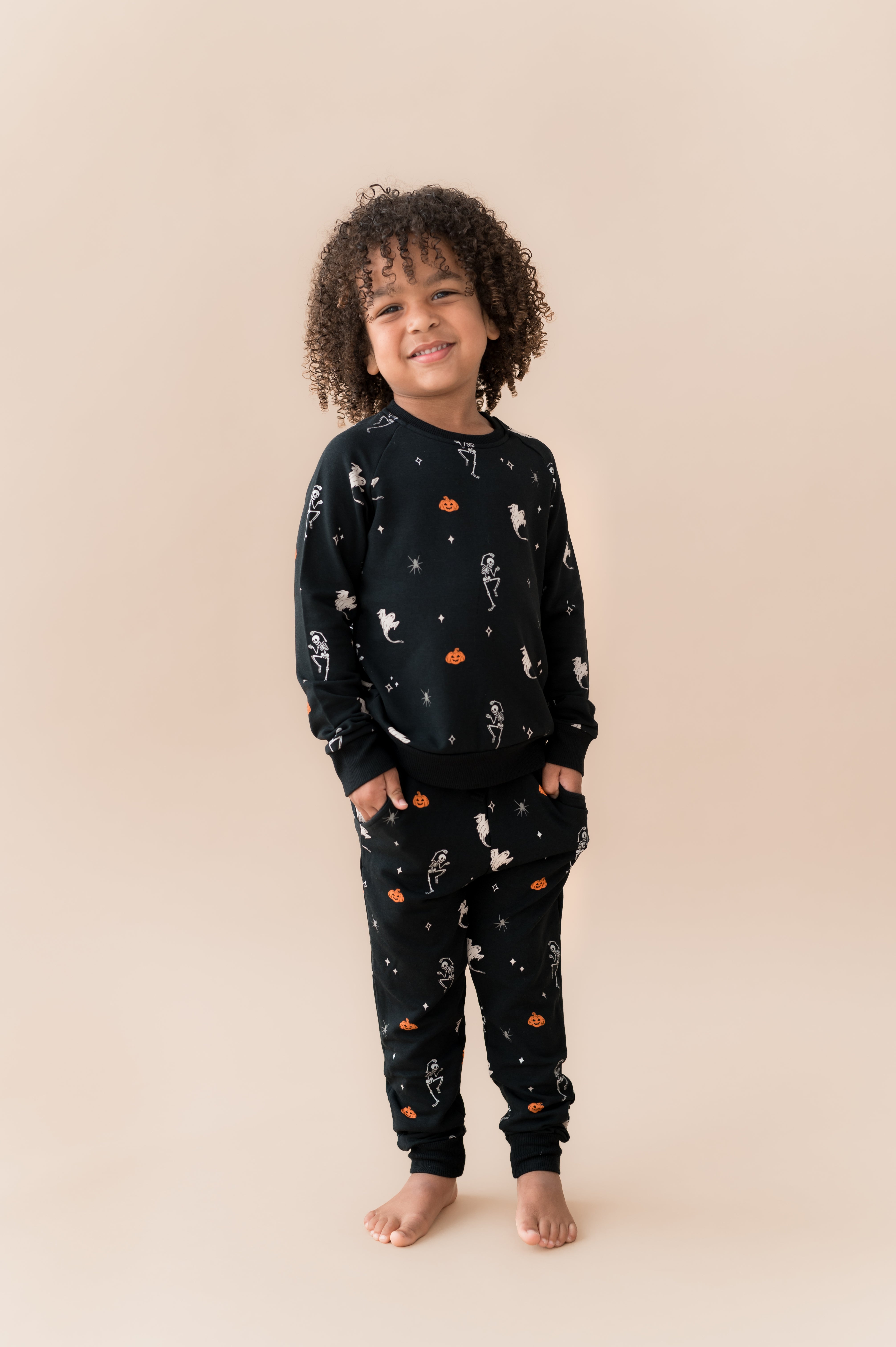 Boy smiling in Long Sleeve Jogger Set in Halloween Friends print on a beige background