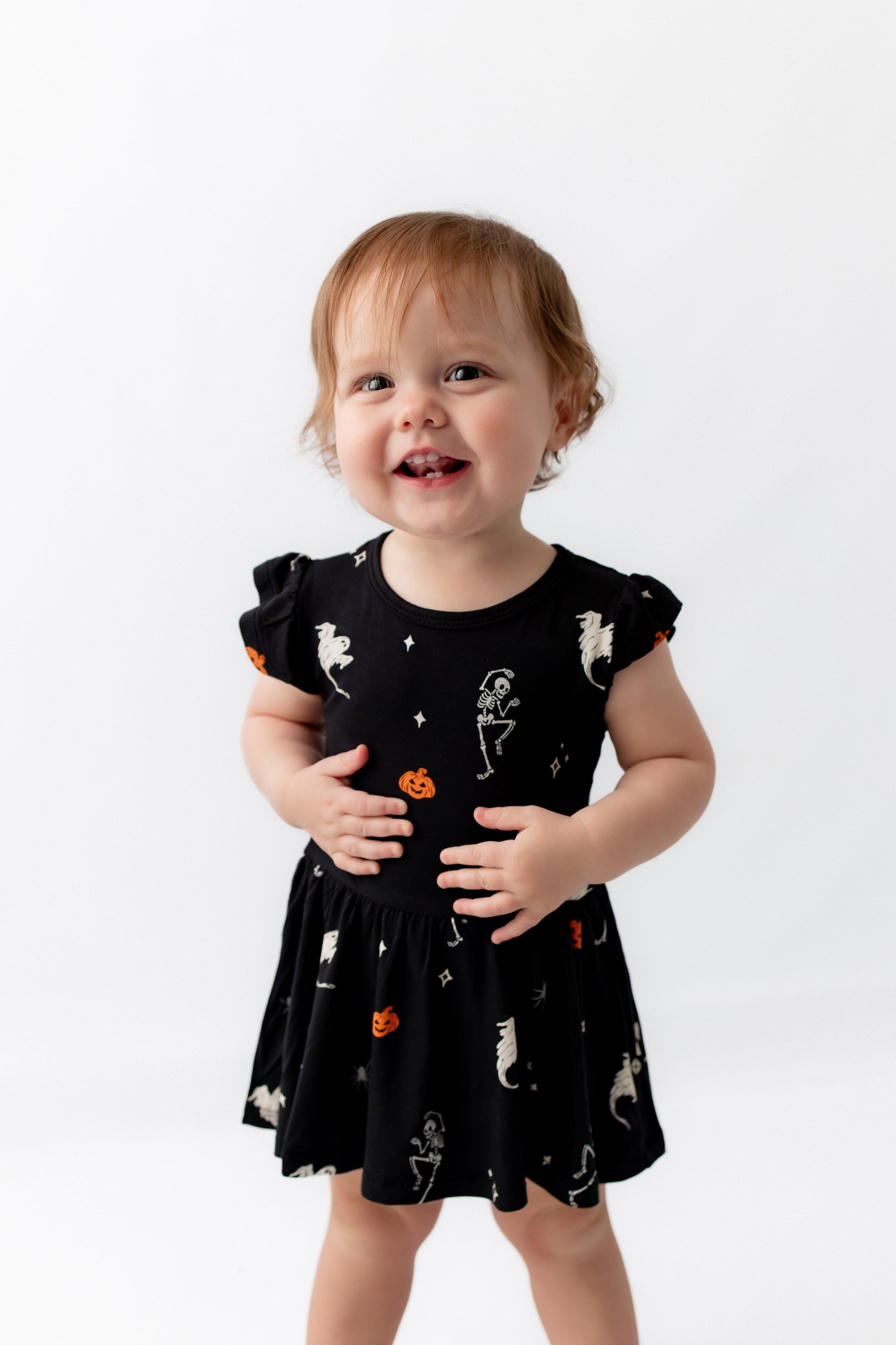 Girl smiling in Twirl Bodysuit Dress in Halloween Friends print on a white background