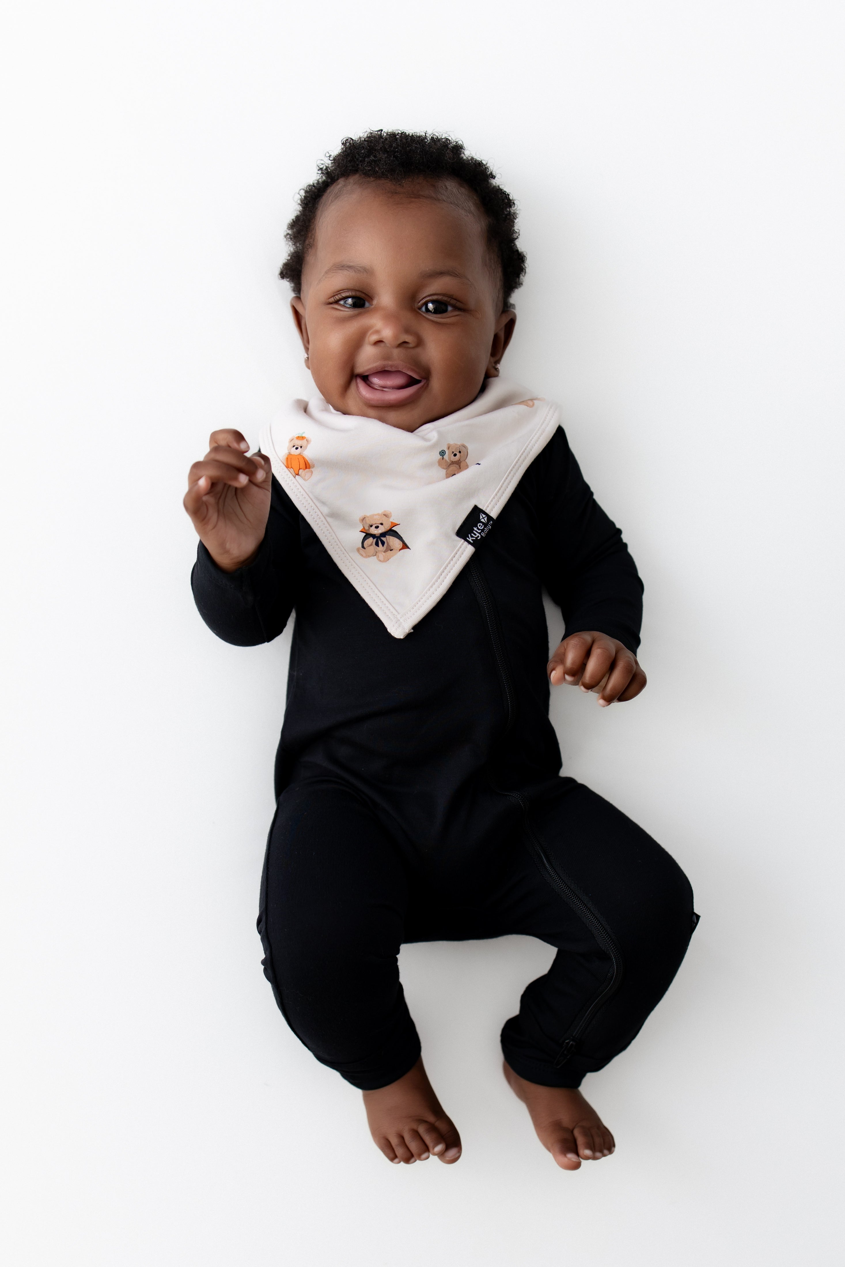 Baby wearing Bib in Halloween Teddy print over a black romper on a white background
