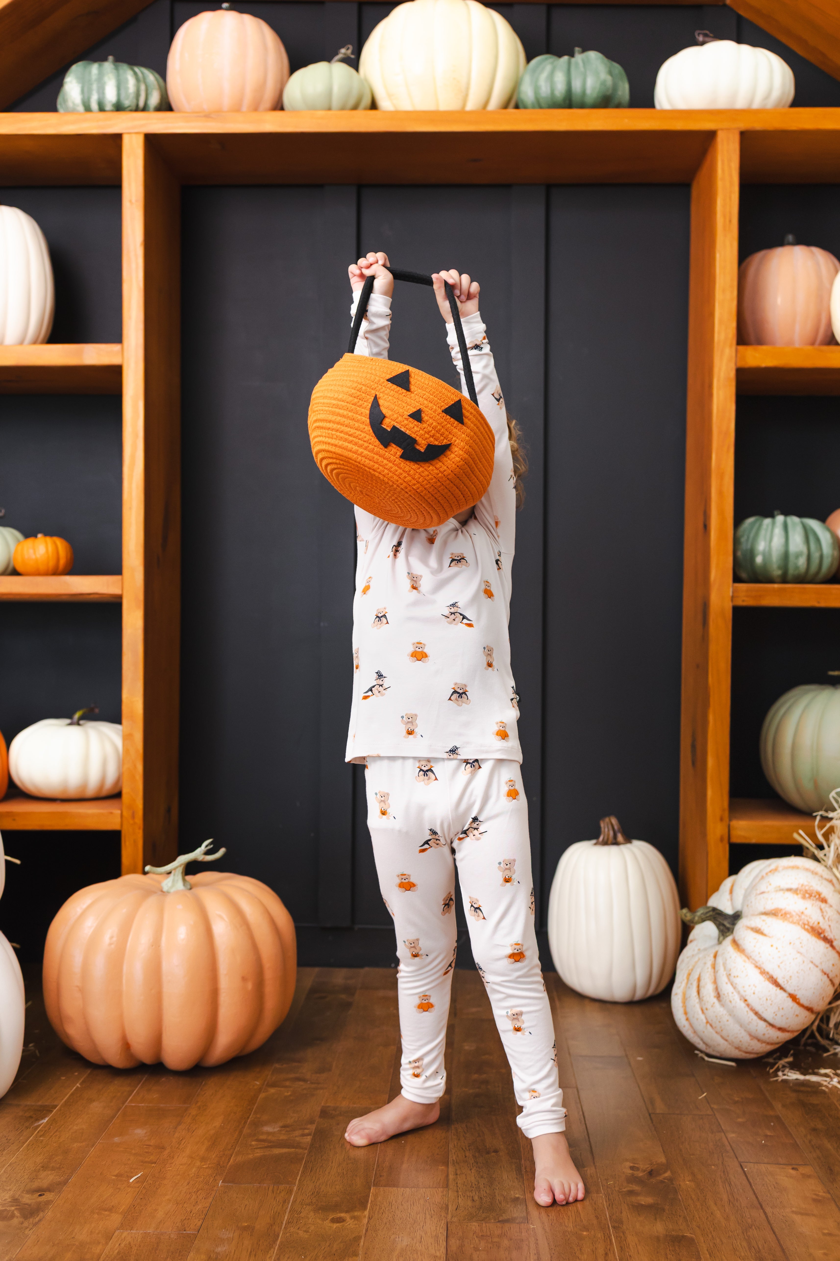 Boy with Halloween pumpkin decorations wearing Long Sleeve Pajamas in Halloween Teddy print 