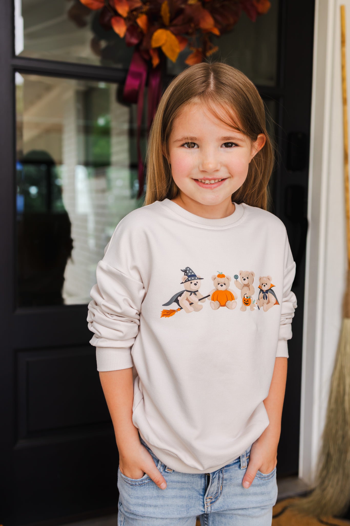 Girl wearing Beige Sweatshirt with Halloween Teddy print in its center standing outdoors