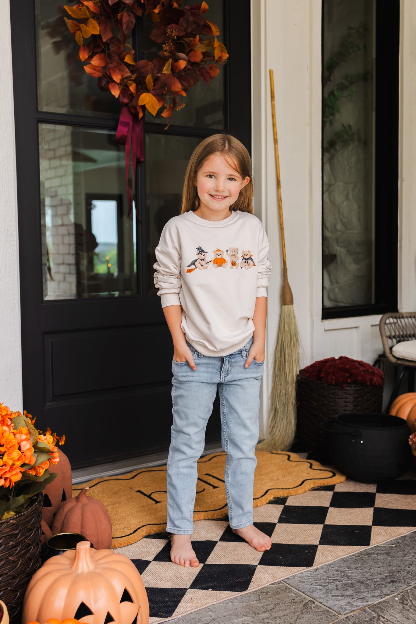 Girl standing outdoors wearing Beige Sweatshirt with Halloween Teddy print in its center