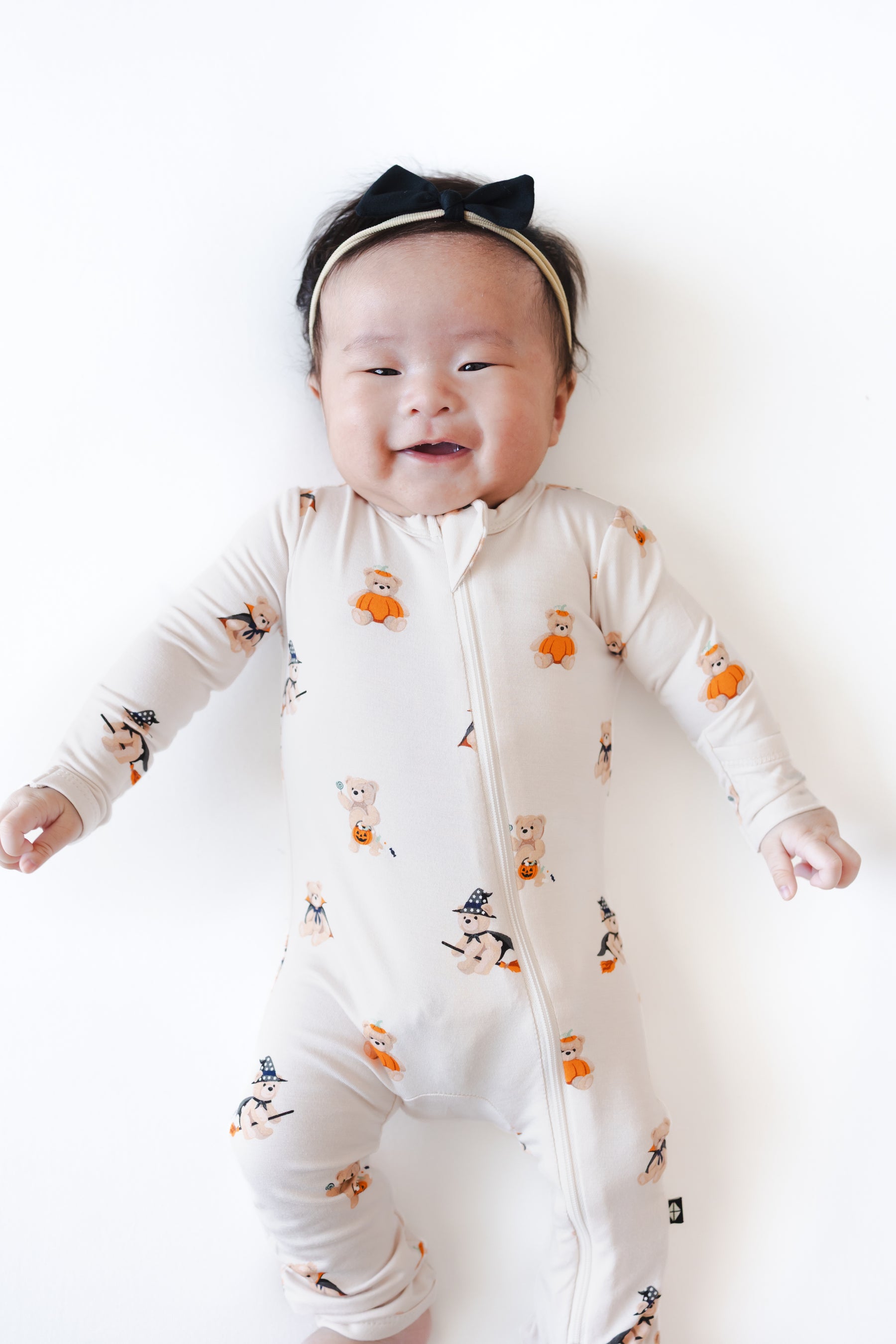Baby wearing Zippered Romper in Halloween Teddy print on a white background