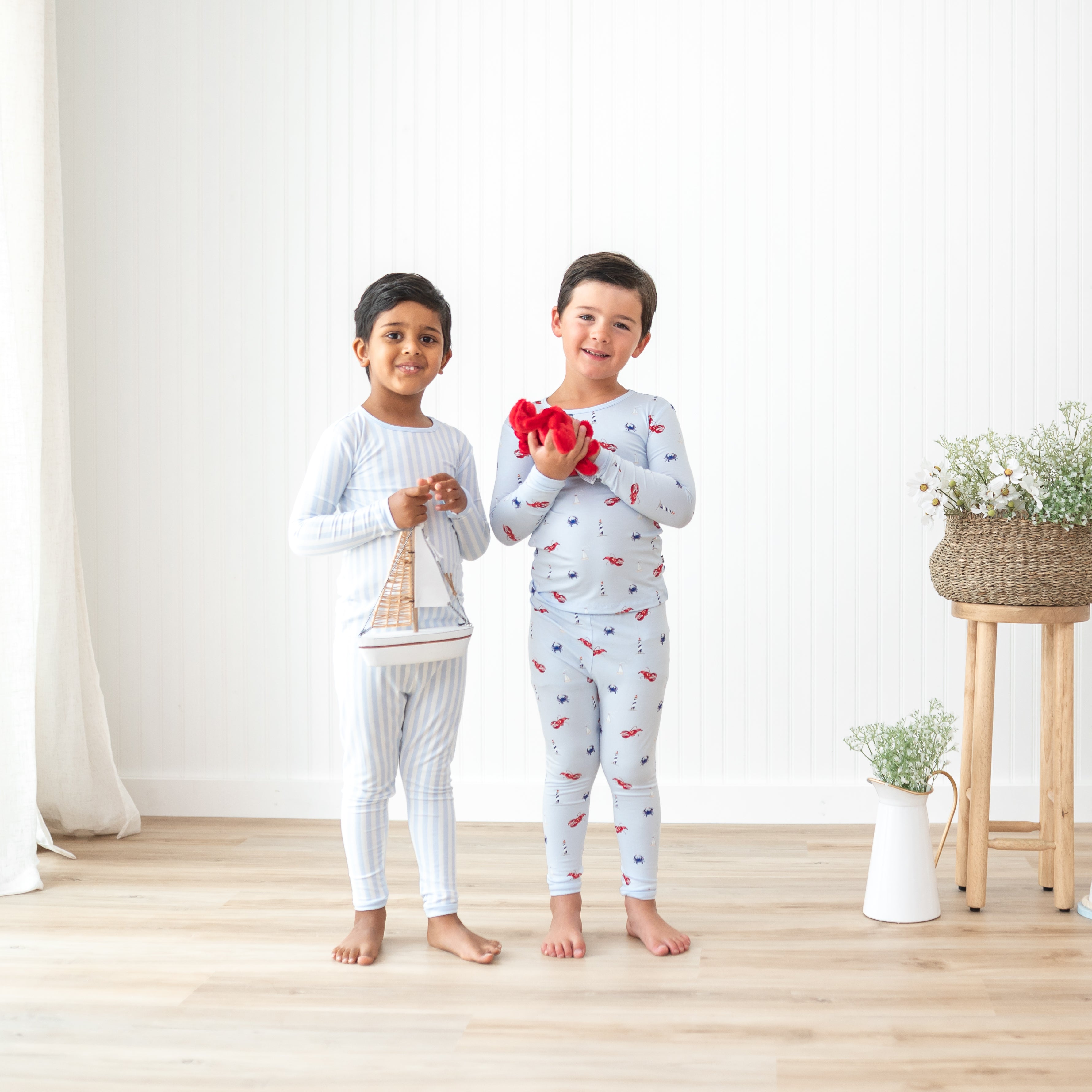 Two boys standing side by side holding stuffed toys wearing Small Stripe and Harbor Long Sleeve Toddler Pajamas