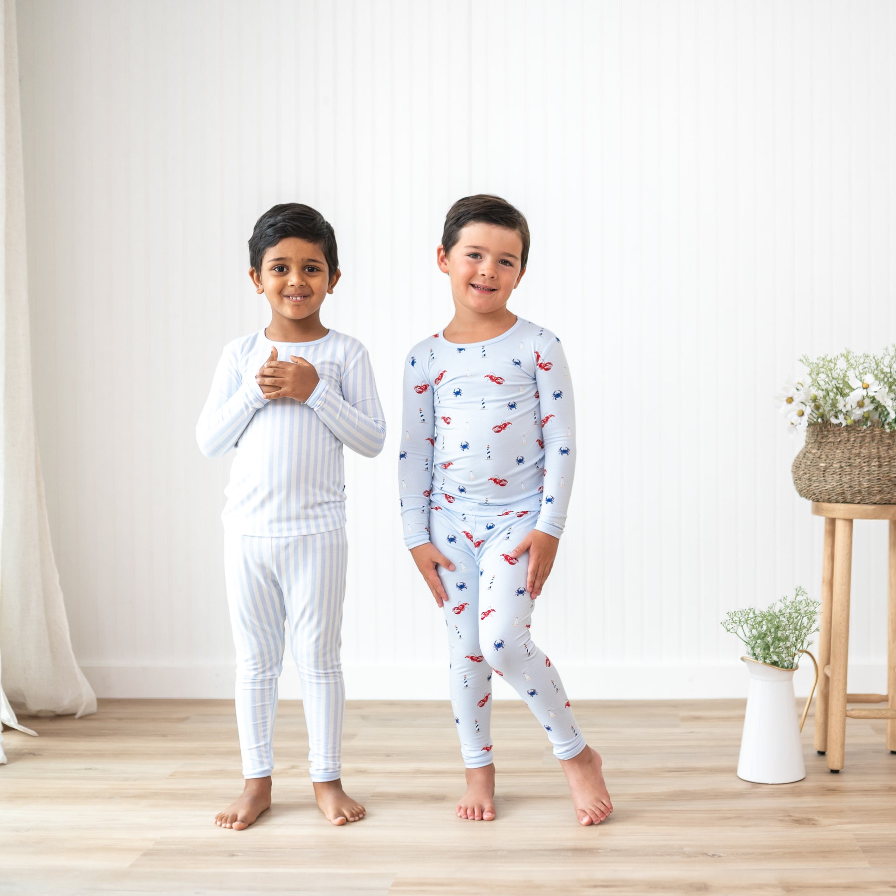 Two boy models standing side by side wearing the Long Sleeve Pajamas in Small Mist Stripe and Harbor