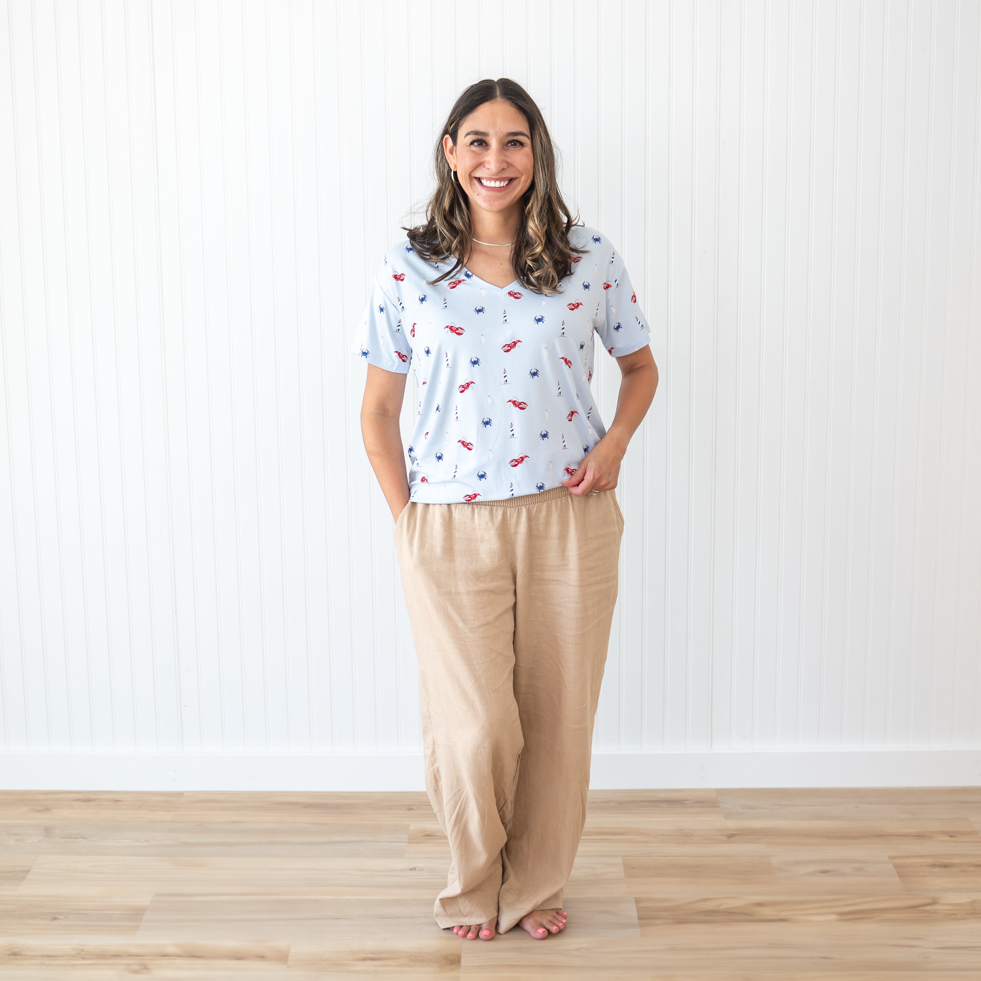Smiling female model wearing the Women's Relaxed Fit V-Neck in Harbor paired with tan linen pants
